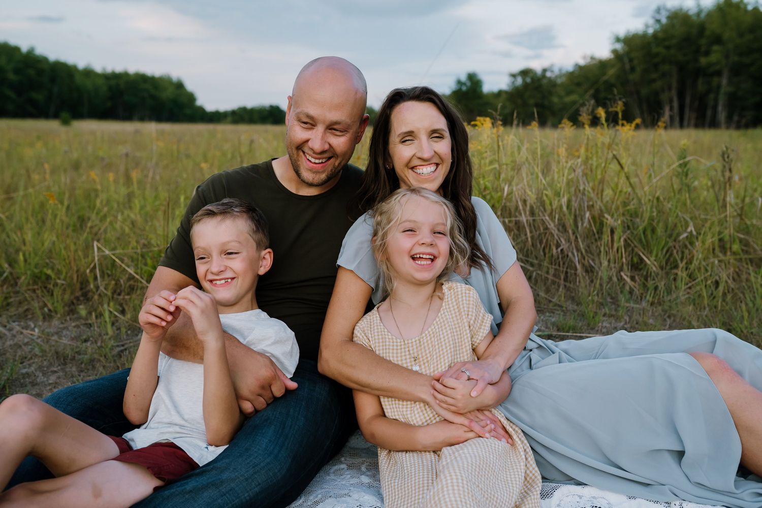 Family of four laughs while sitting on blanket