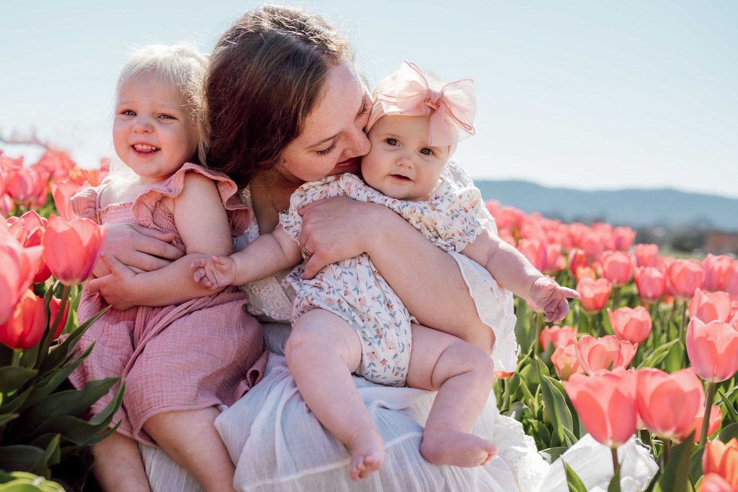 Mom kisses her baby girls during photoshoot