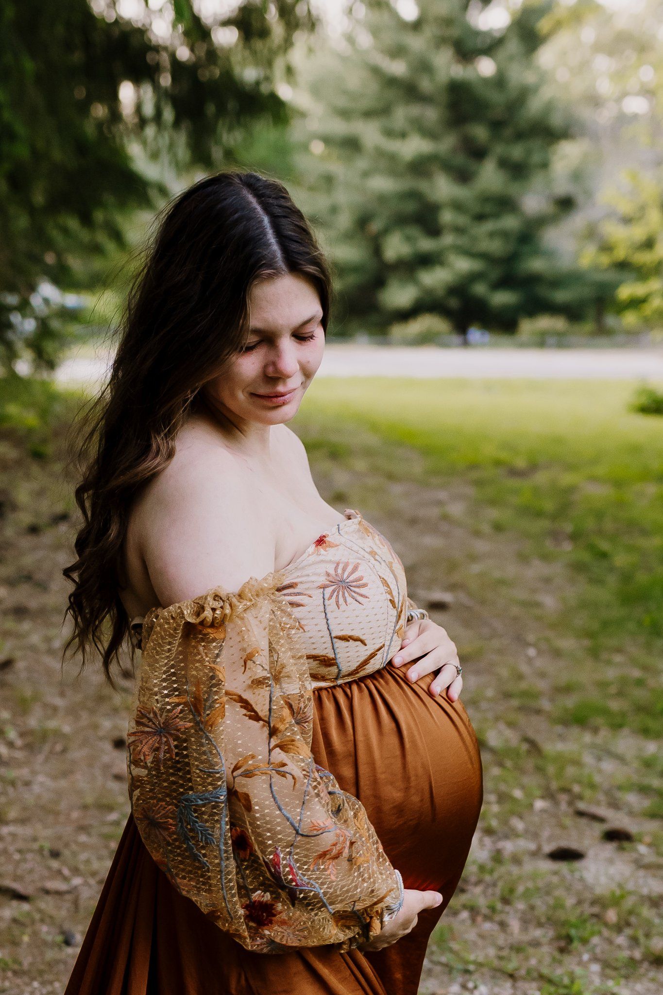 Woman holds pregnant belly and looks down her shoulder