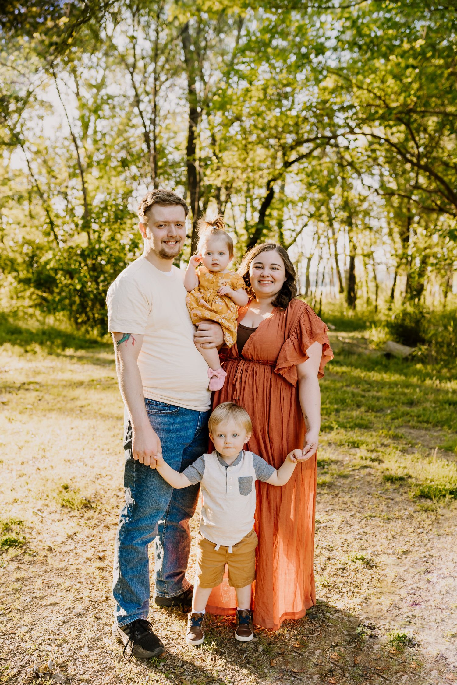 Family of four stands and smiles at the camera during summer sunshine family photos