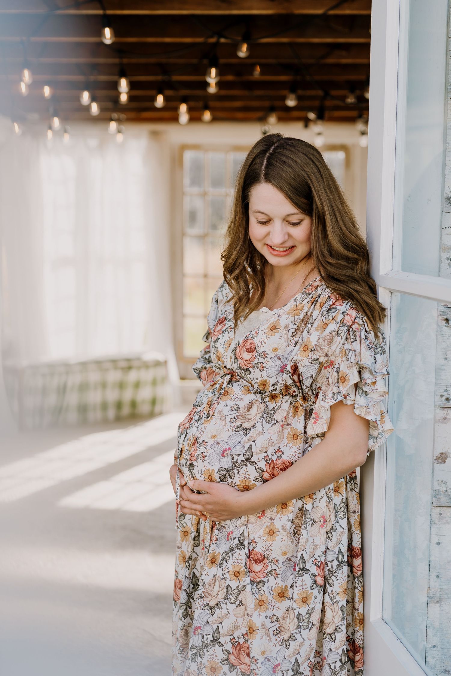 Mom smiles down as she holds her bump during maternity photos at the holmstead studio in karns