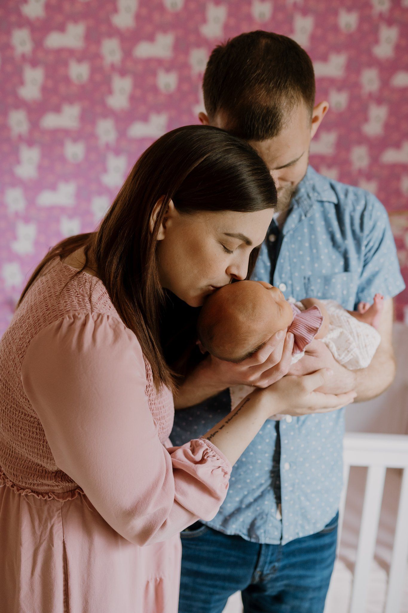 Man holds newborn and woman kisses the baby's head