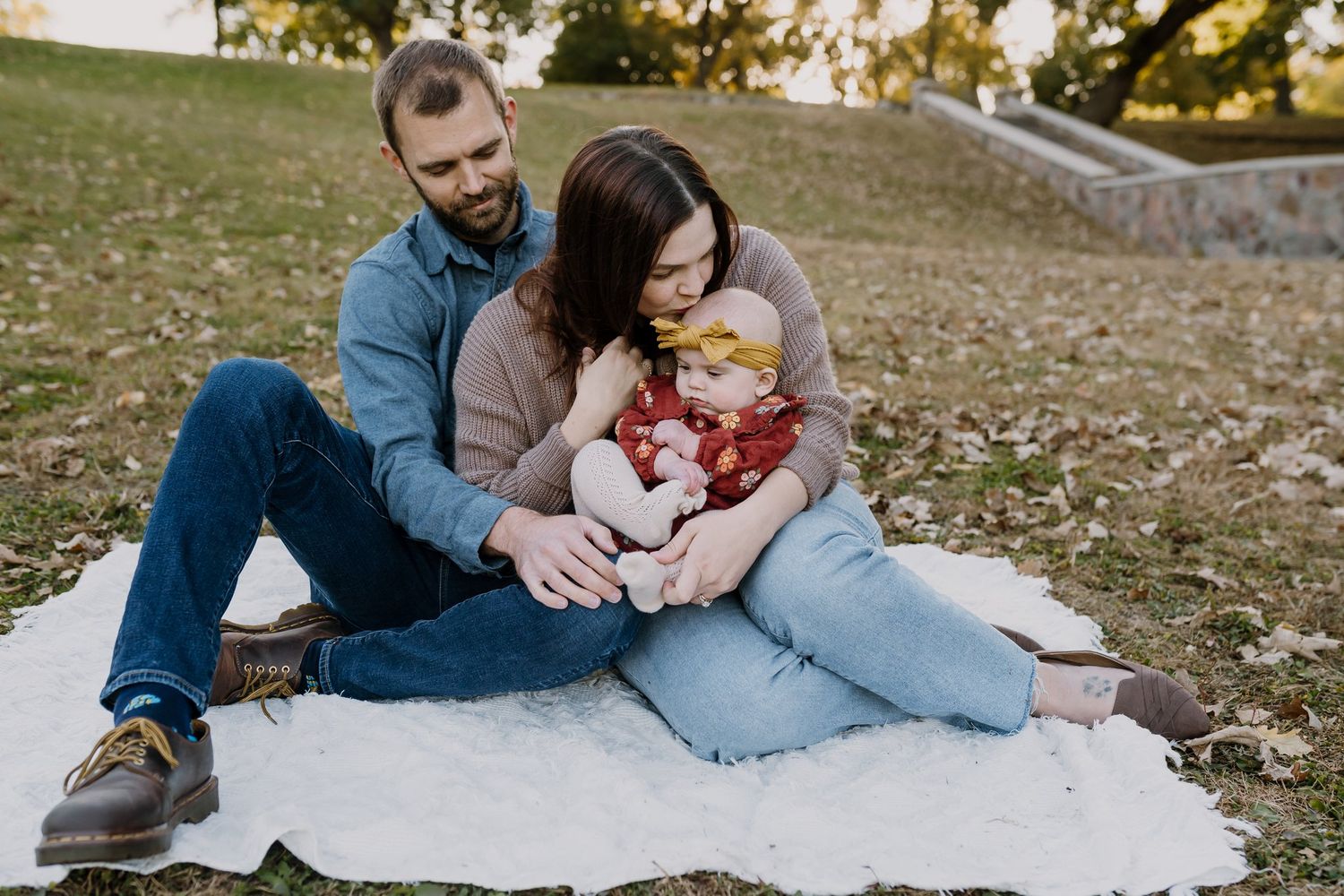 Family of three cuddles on a blanket outside after booking pictures