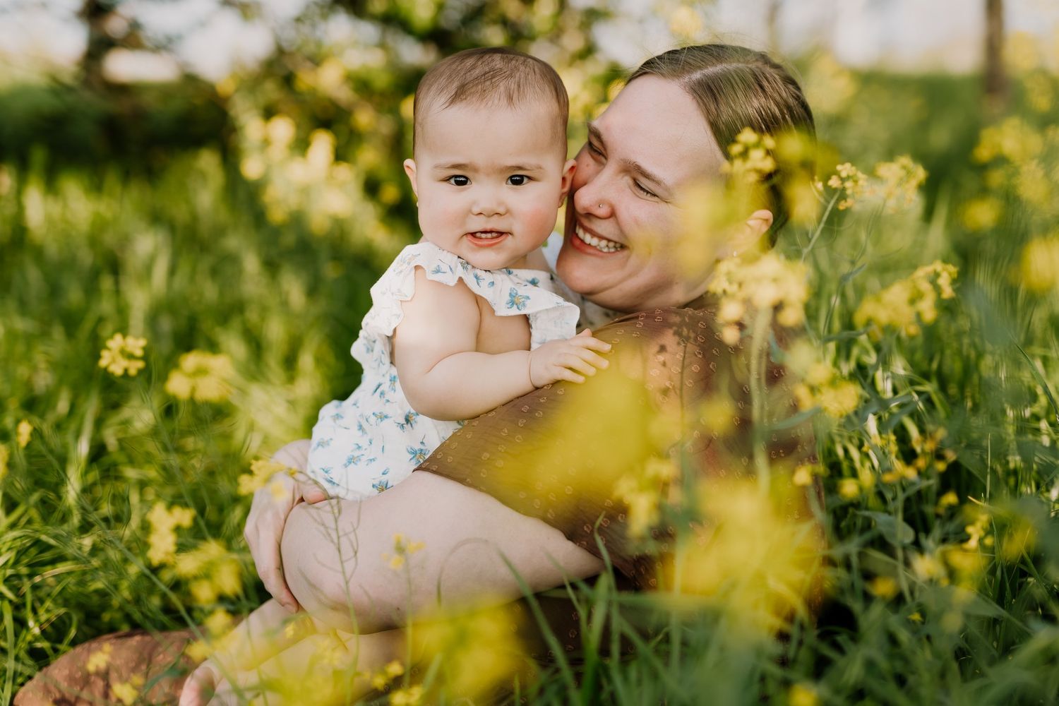 Mom snuggles her daughter during mommy and me photos downtown knoxville in the mustard flower field