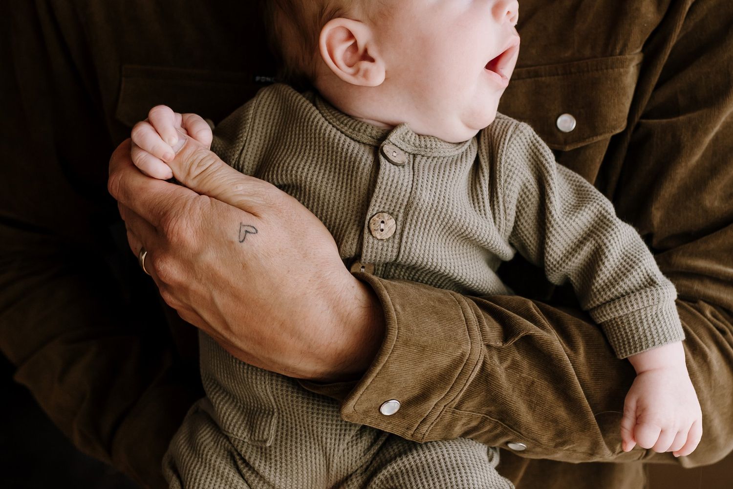 Close up of newborn holding dad's hand