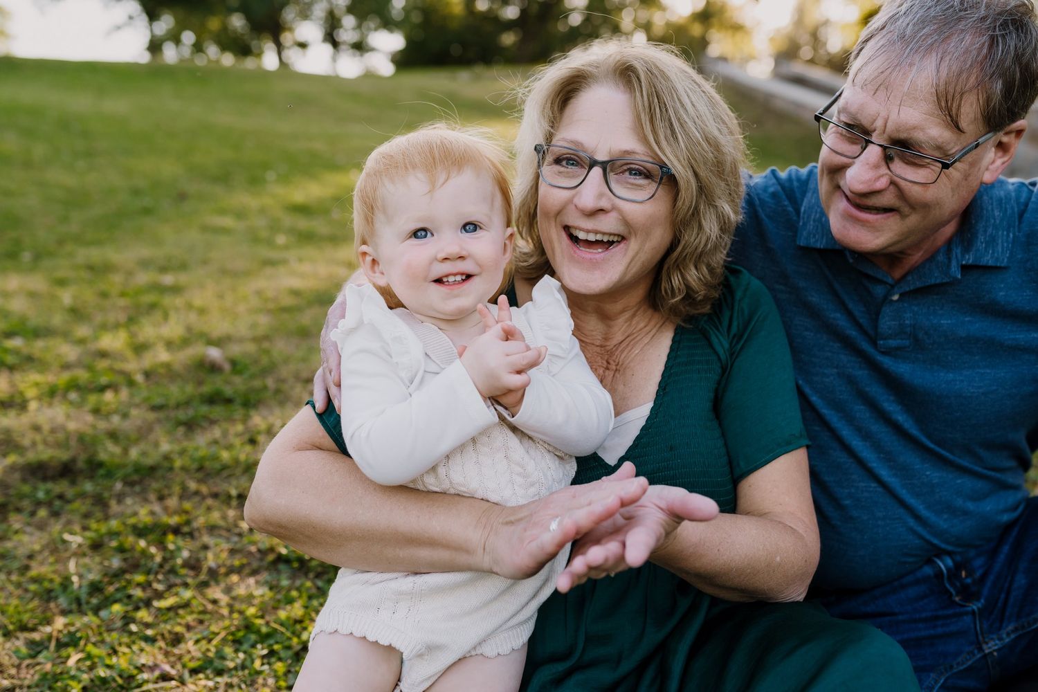 Grandma plays patty cake with her one year old granddaughter and they smile together at the camera
