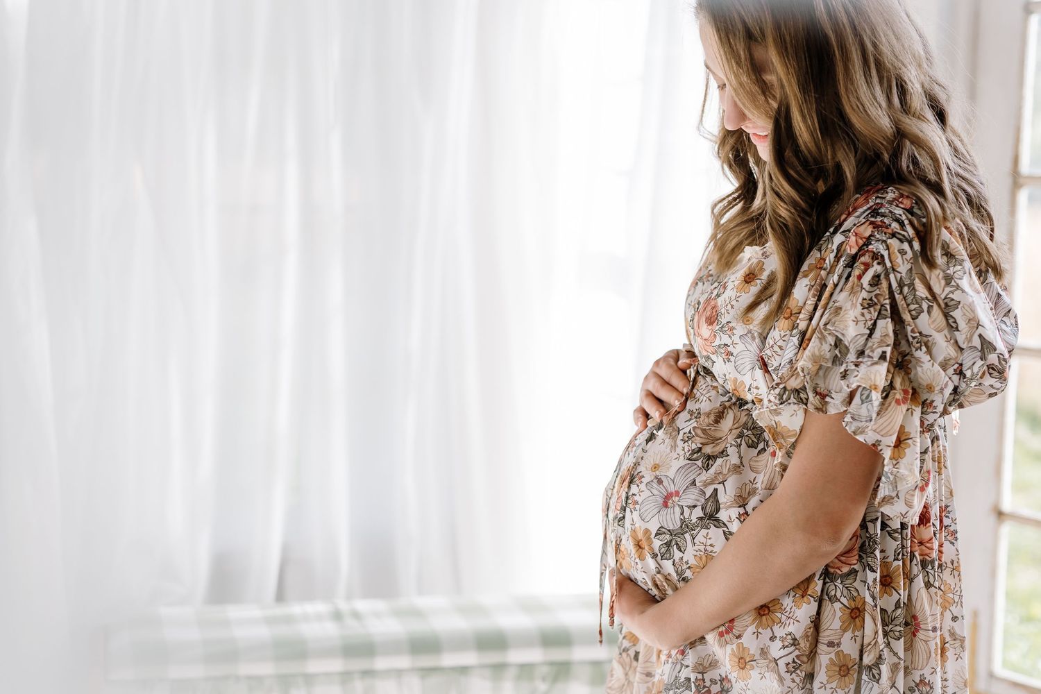 Mom smiles as she looks down at her bump during maternity photos at the holmstead studio in karns