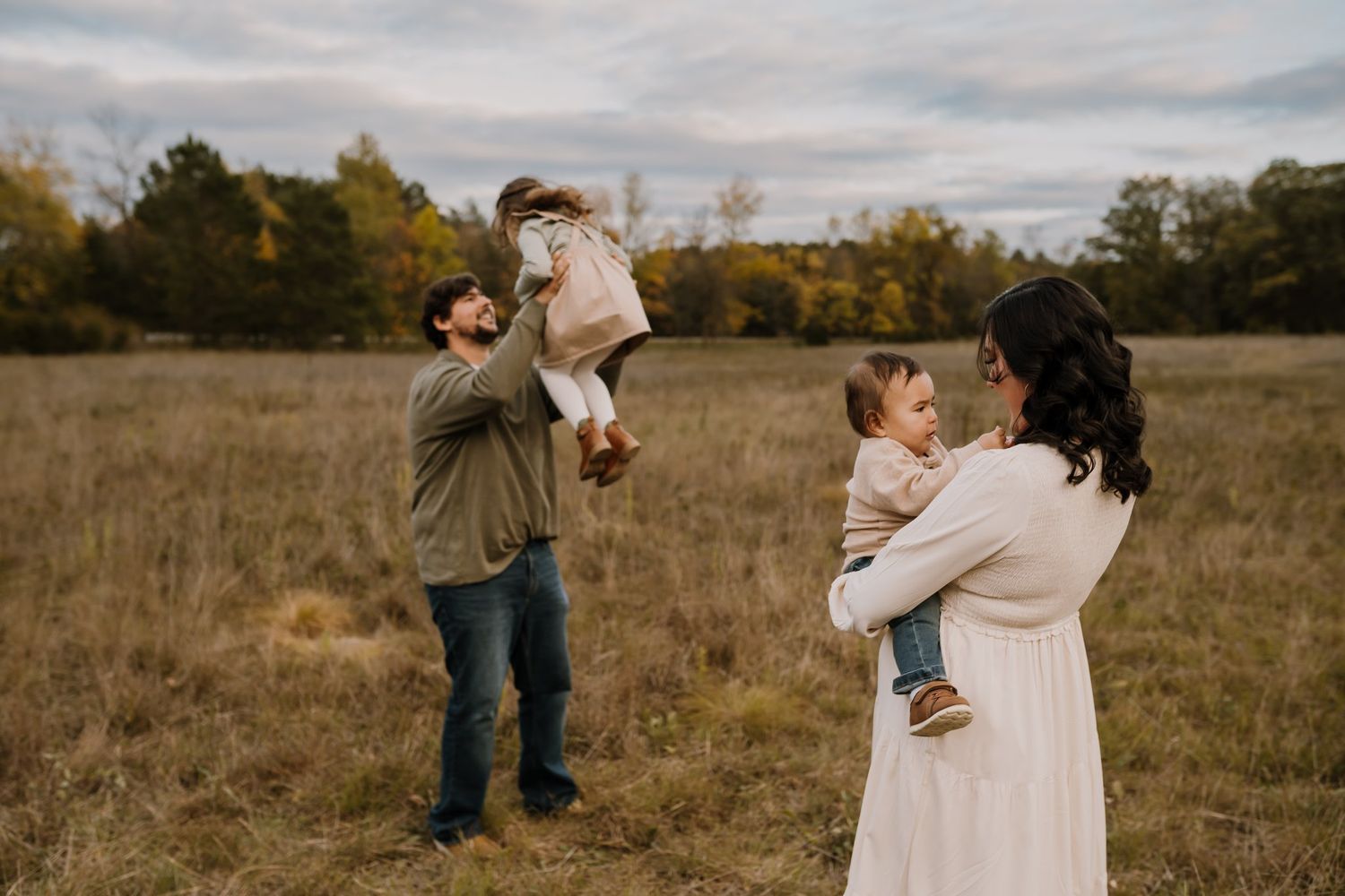 Family of four plays in a field during fall family photos with toddlers