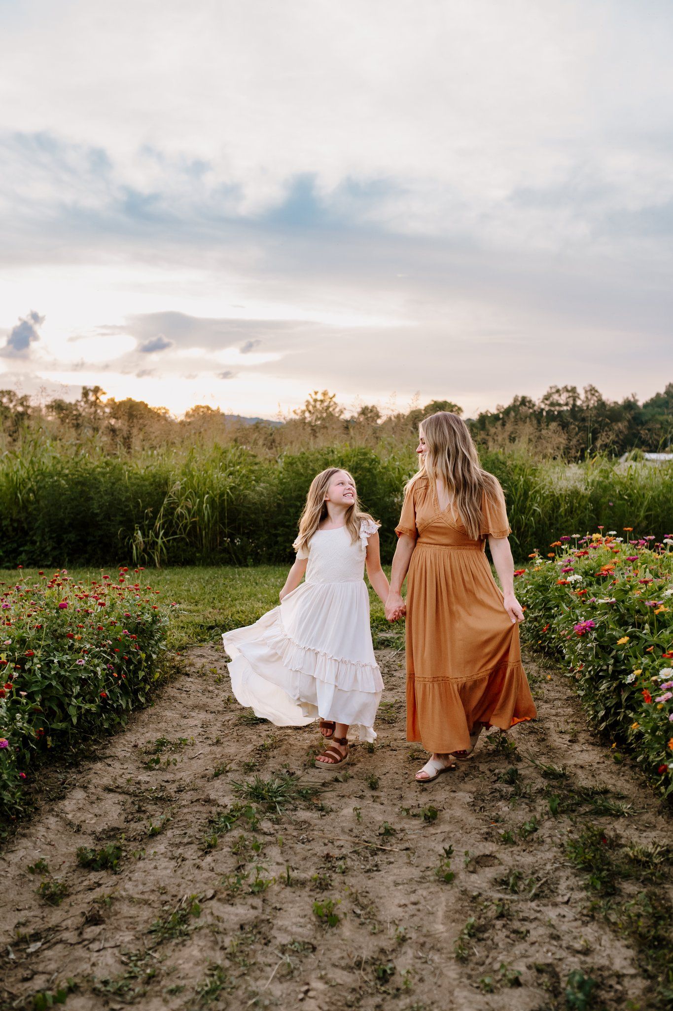 Mom walks hand in hand with her 8 year old through a u pick flower field