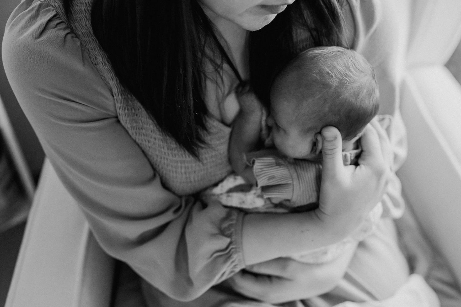 mom holds newborn baby close to her heart during newborn baby pictures