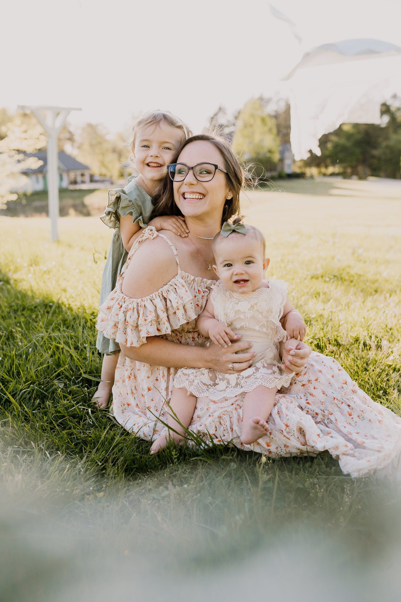 Mom sits in the grass with her daughters