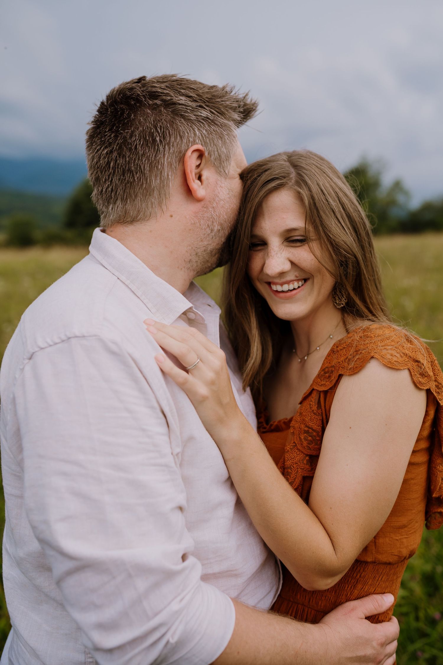 Man embraces woman and whispers in her ear as she laughs