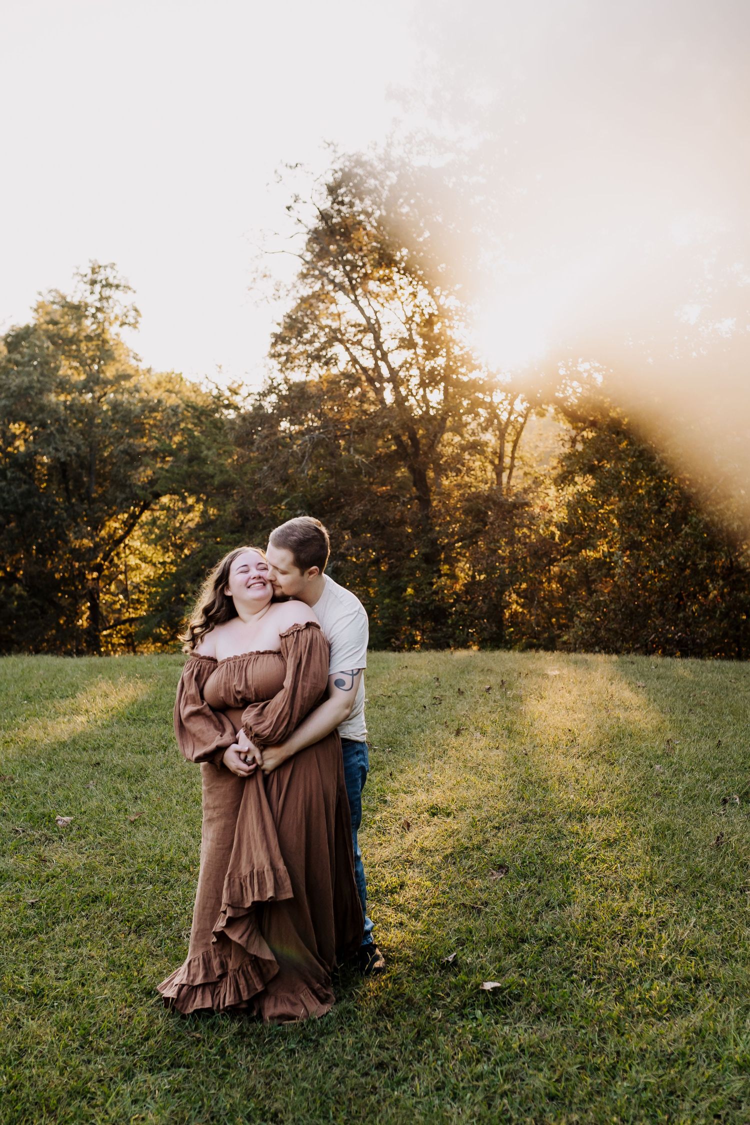 Man embraces woman from behind and whispers in her ear as she laughs