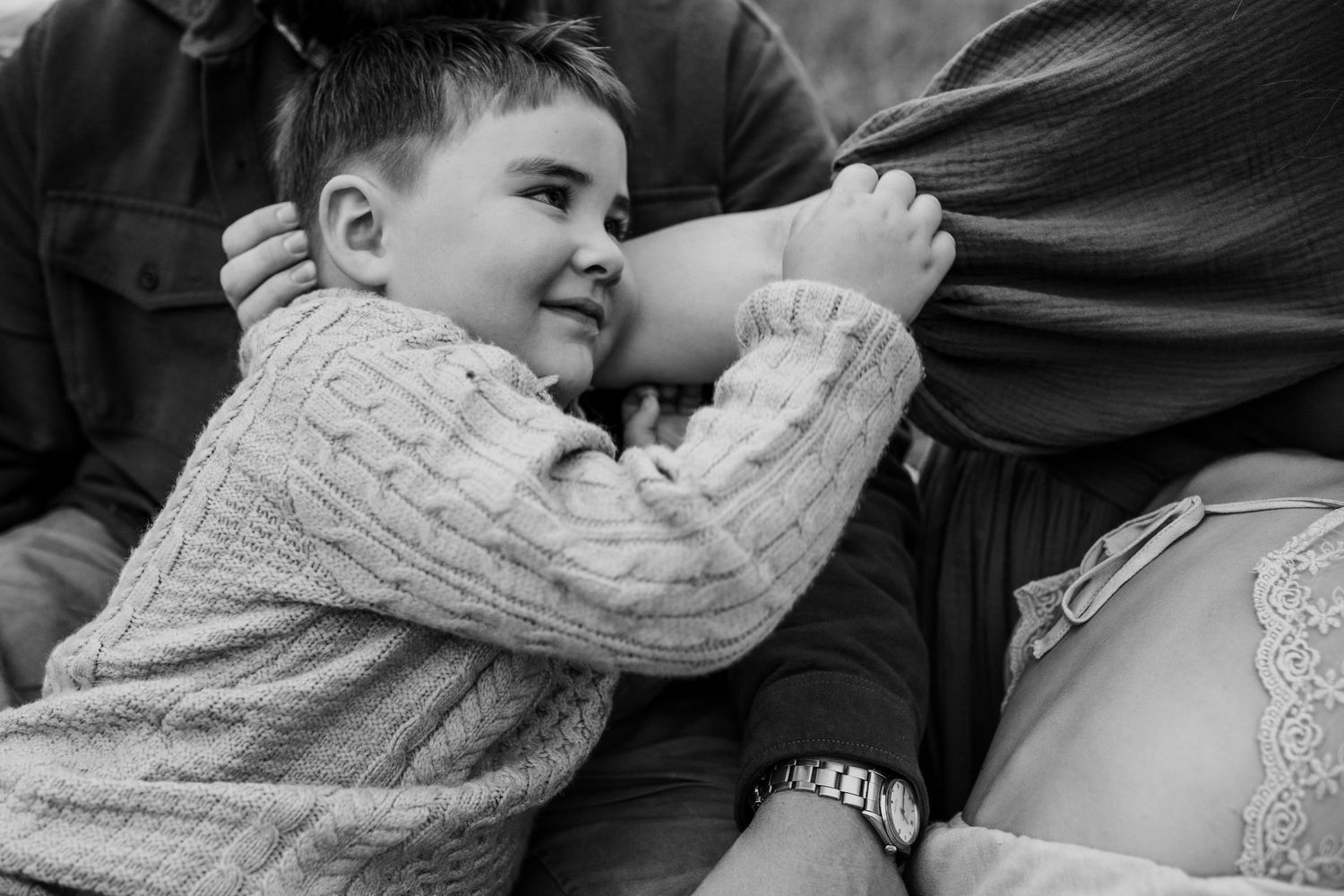 Toddler snuggles against his mom's arm during family photos in Cades Cove