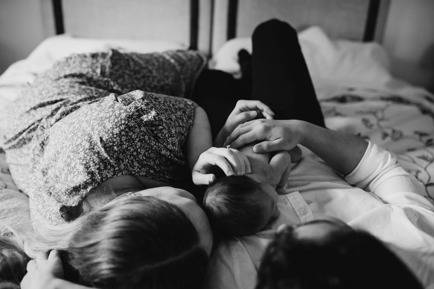 Parents lay on bed and snuggle their newborn