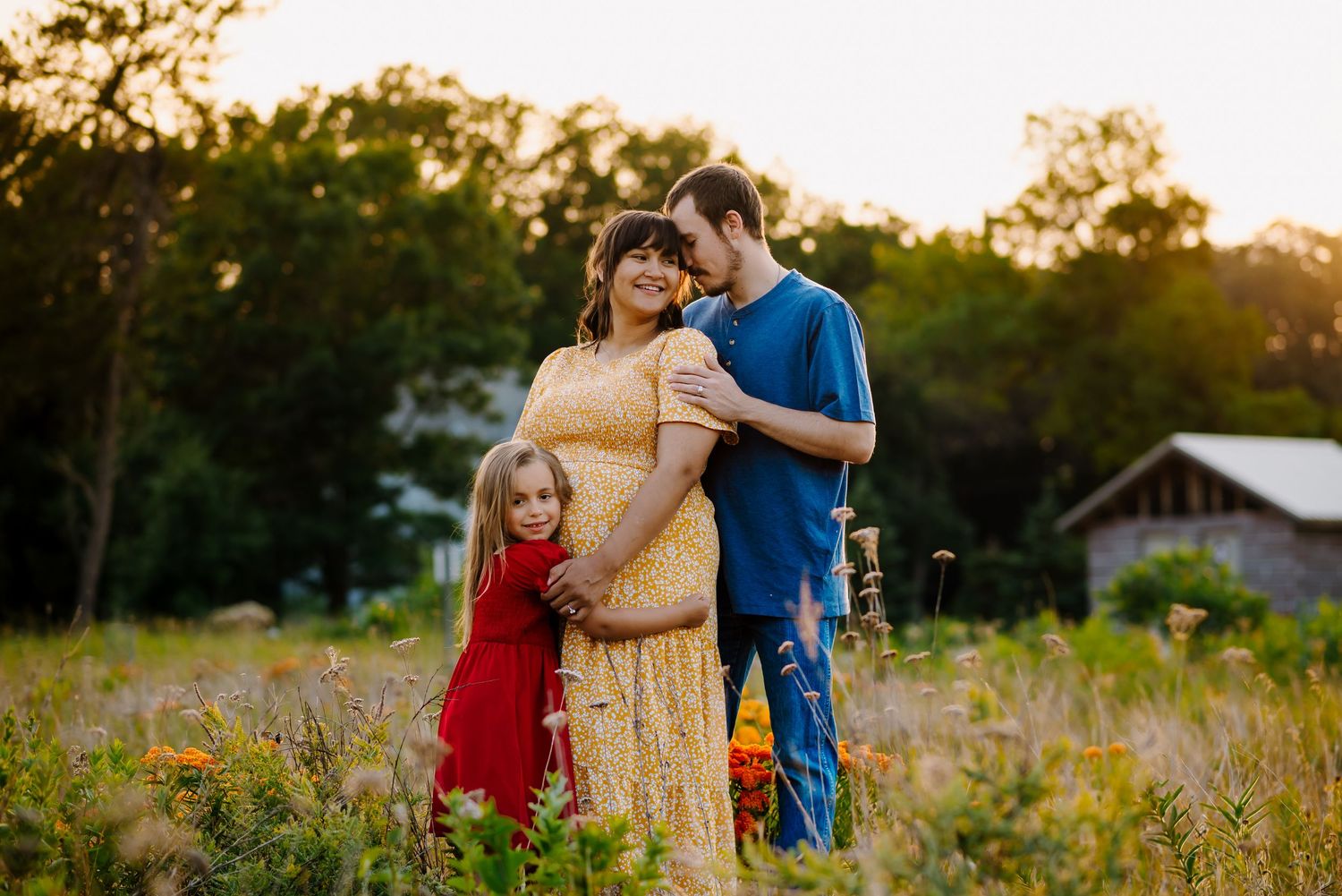 Family stands together in a field of flowers during maternity pictures