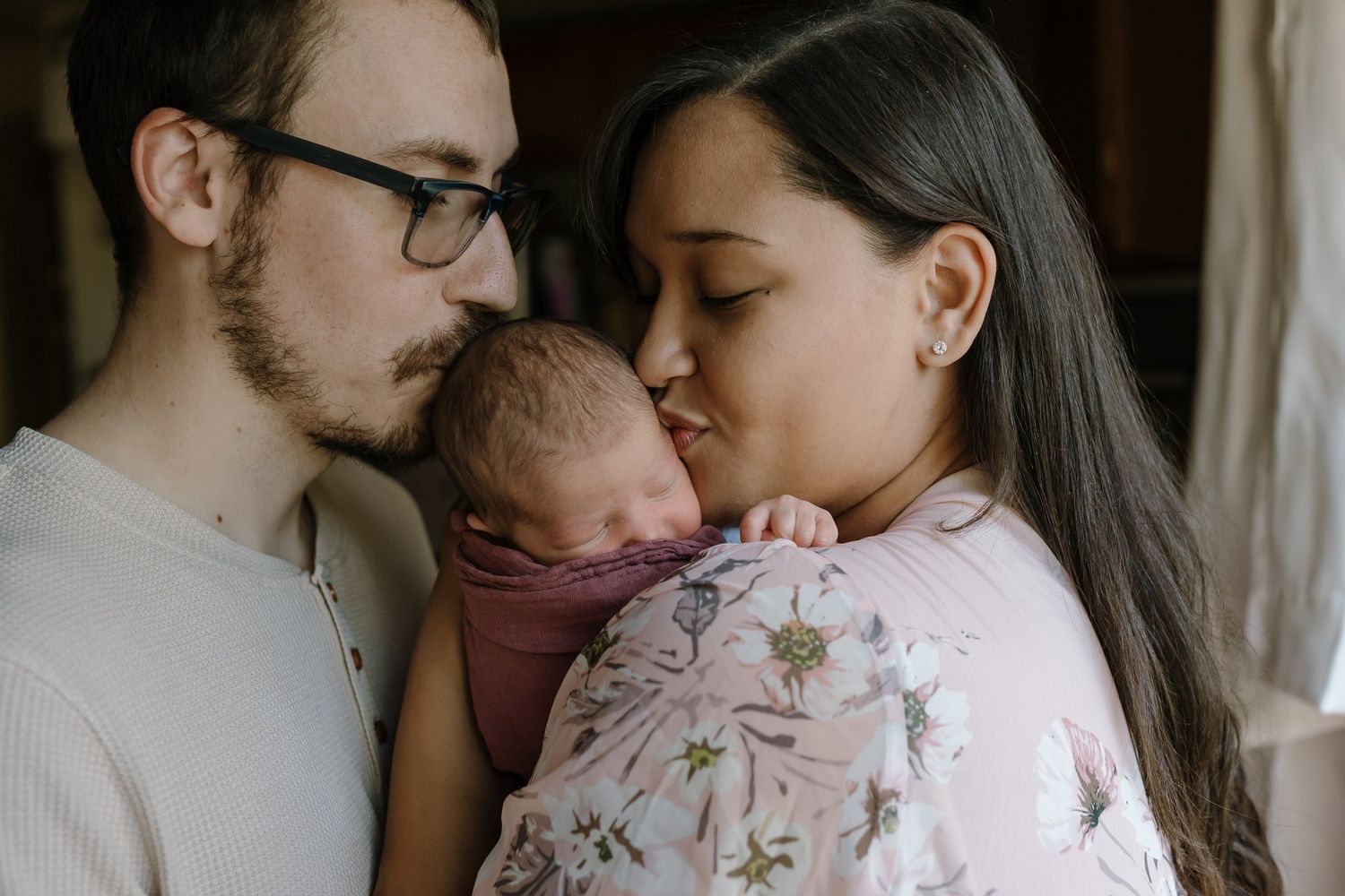 Parents kiss their newborn baby during maryville newborn photos