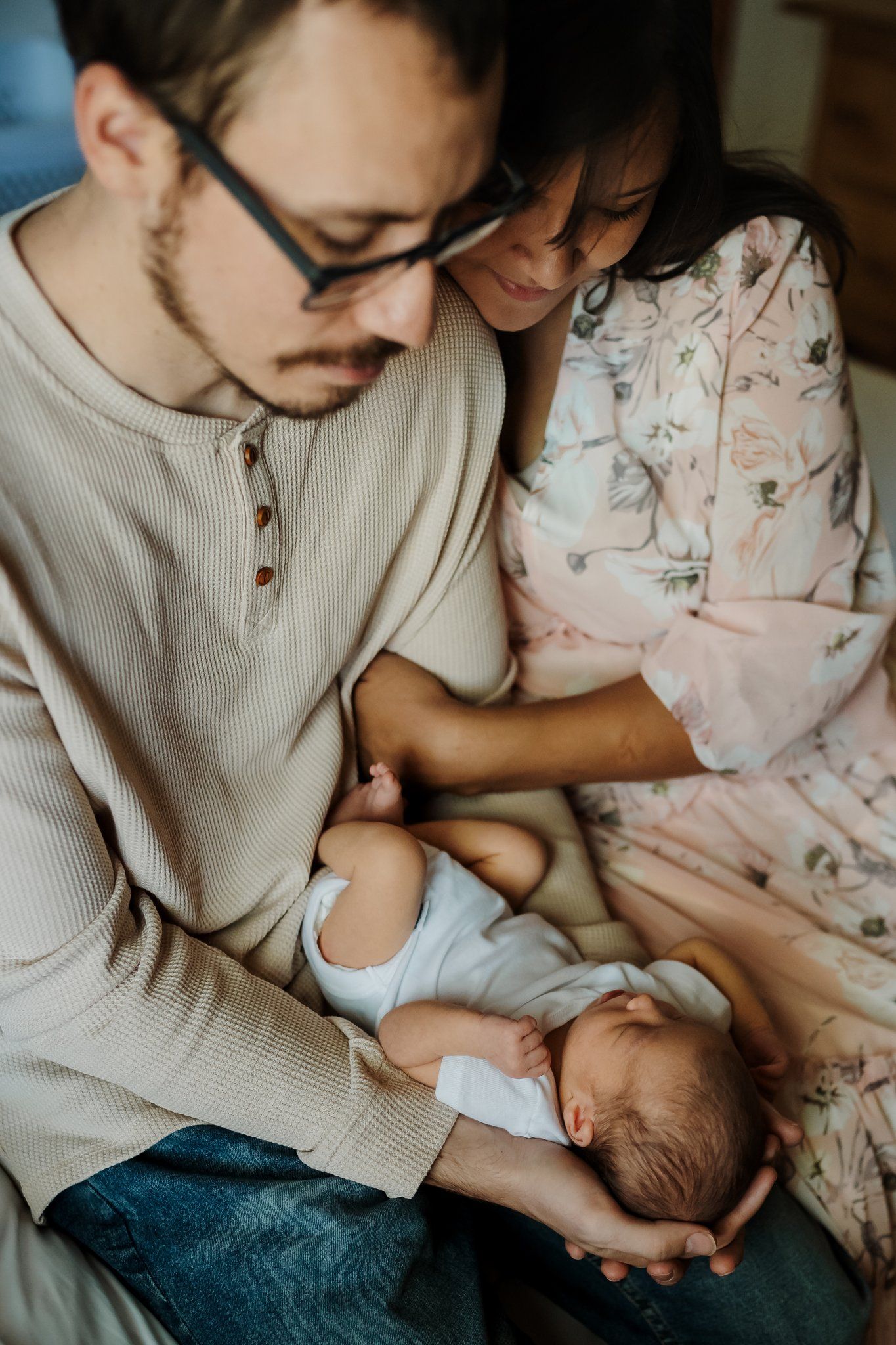 Mom and dad snuggle baby during lifestyle newborn photography session