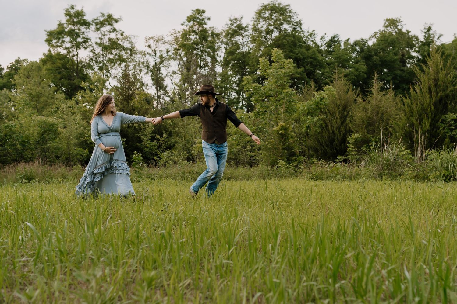 Mom and dad run through a field during couple maternity photos Maryville Maternity Photographer
