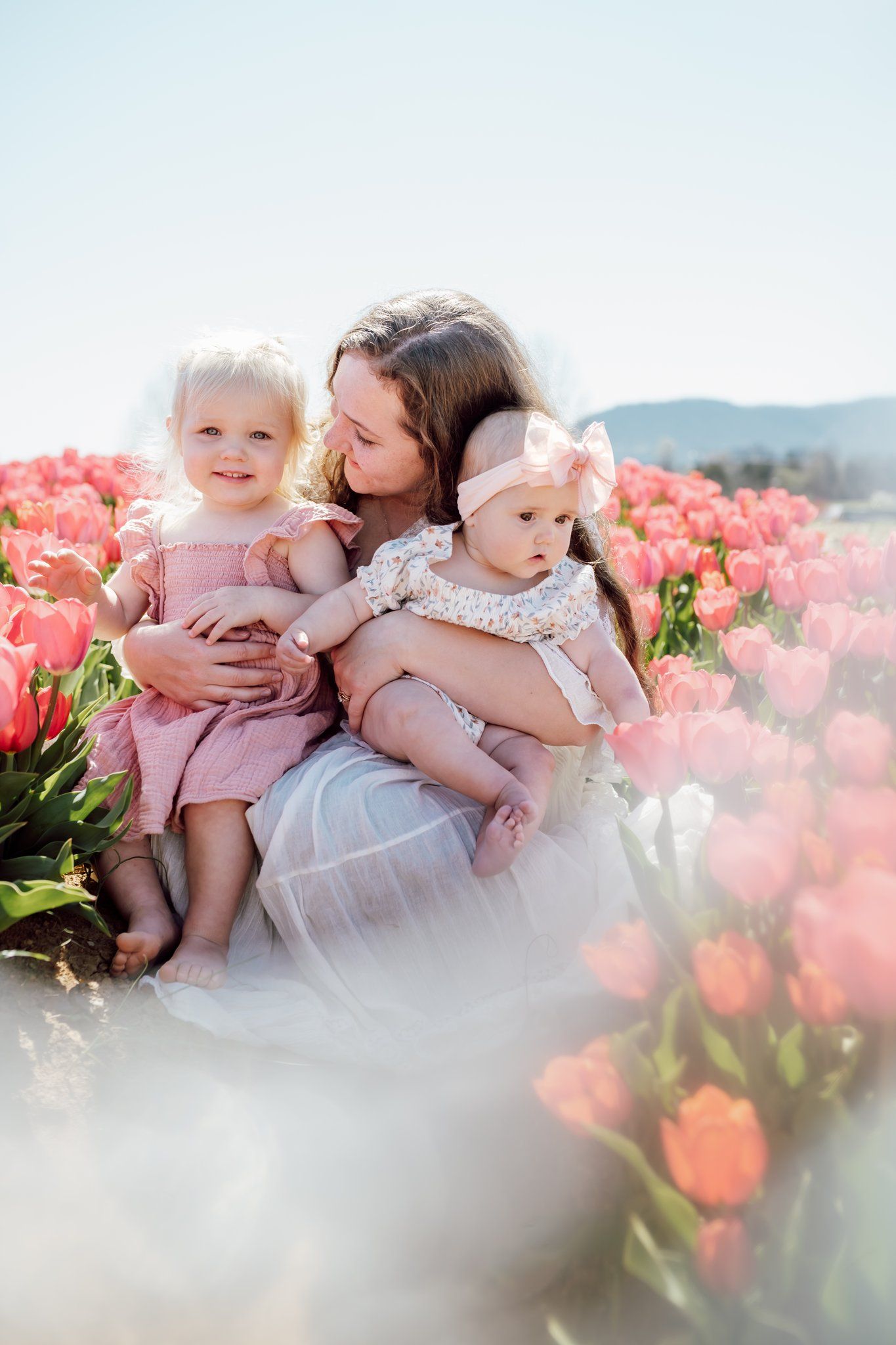 Mom sits with daughters in tulip field near knoxville for motherhood flower field photos