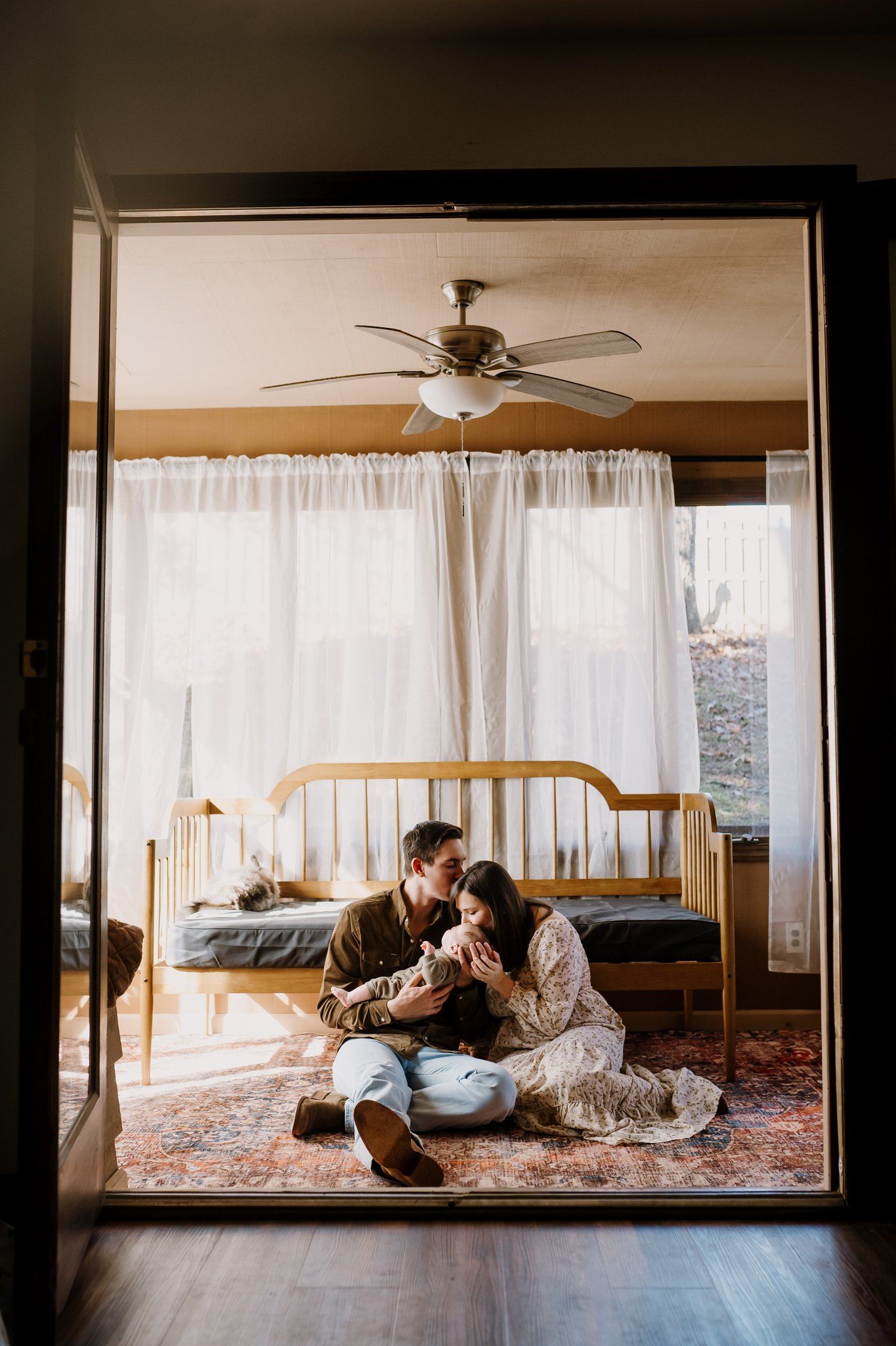 Parents sit on sunroom floor with baby