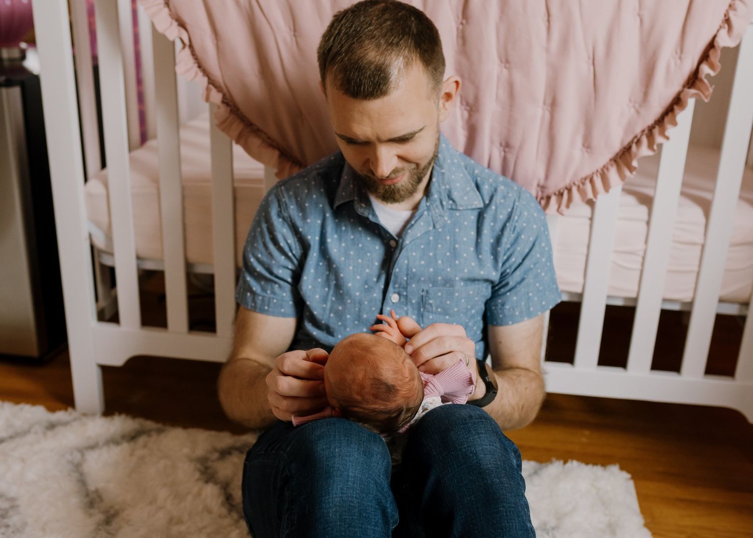 Dad sits on nursery floor with his newborn during in home newborn photos maryville tn