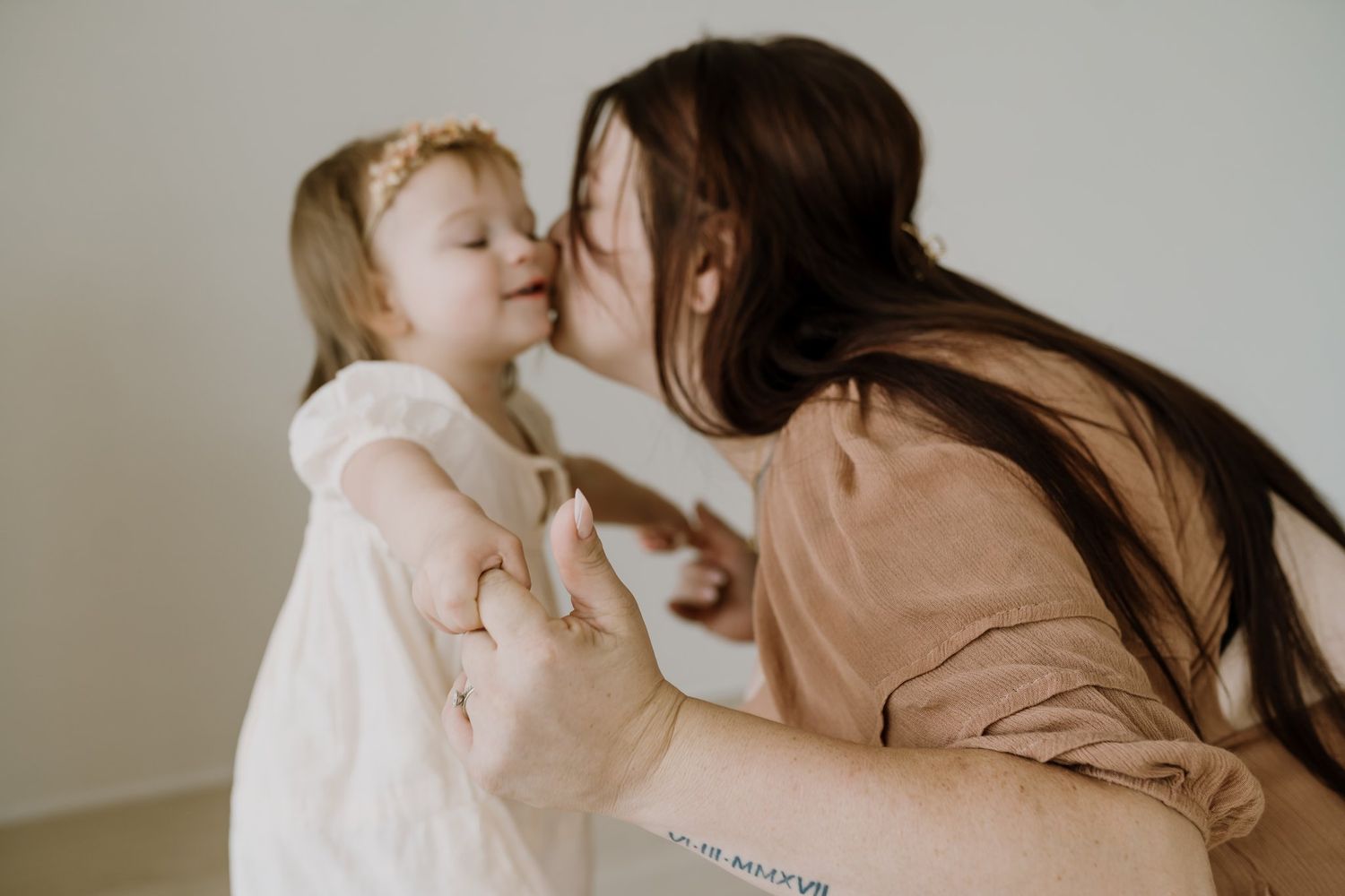 Mom kisses her daughter during studio photoshoot