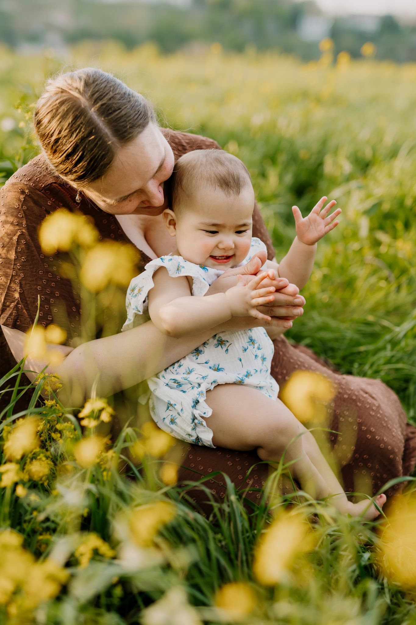 Woman sits in a flower field downtown knoxville and plays with her baby during mommy and me photos