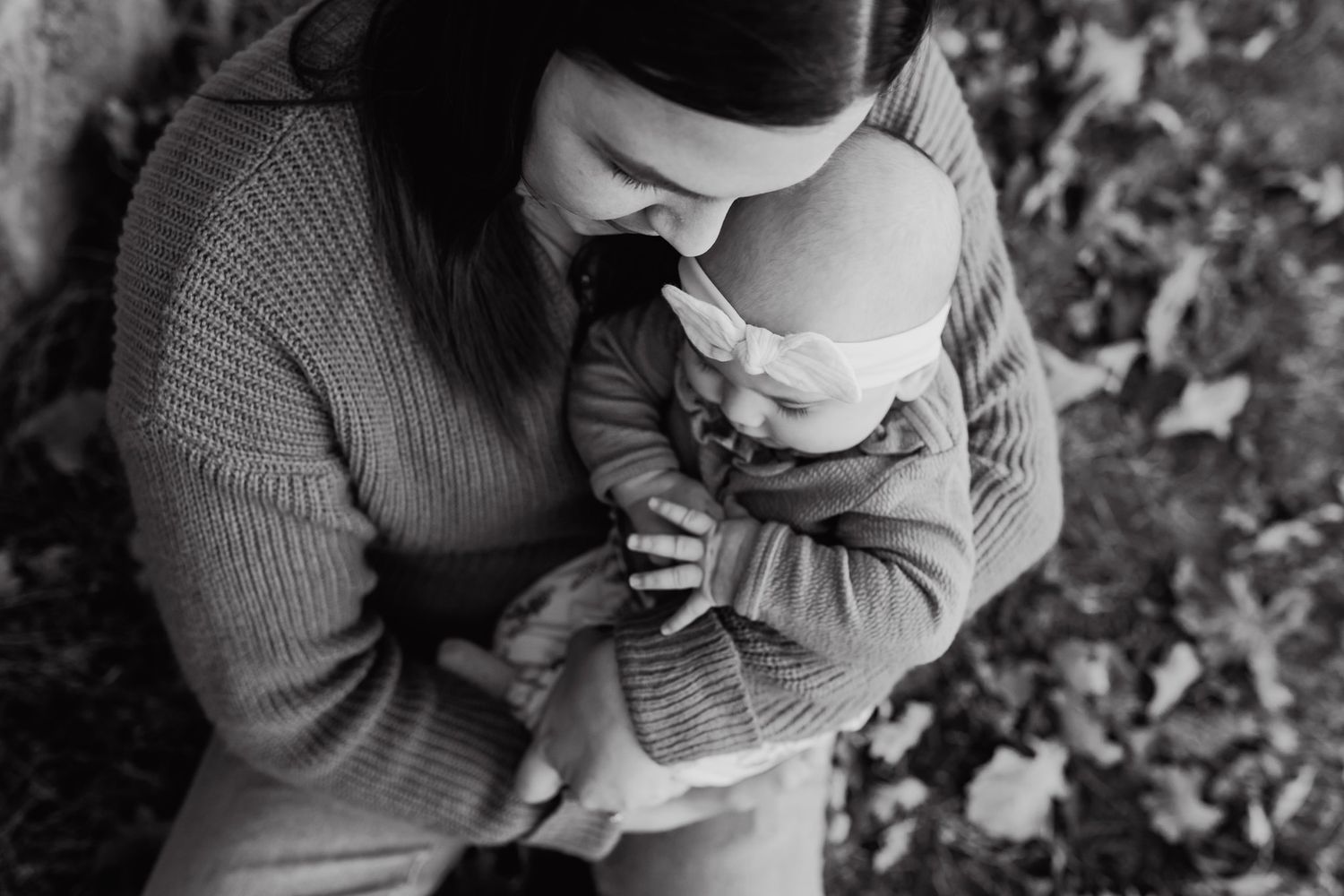 Mom sits in grass at golden hour and snuggles baby girl