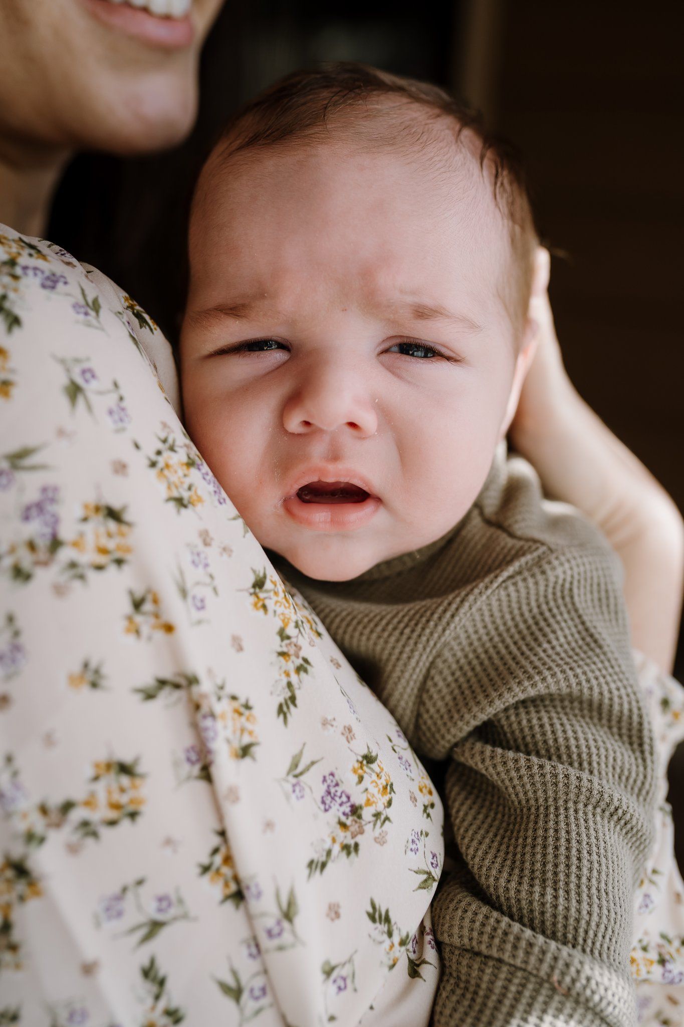 Baby looks at camera from mom's arms