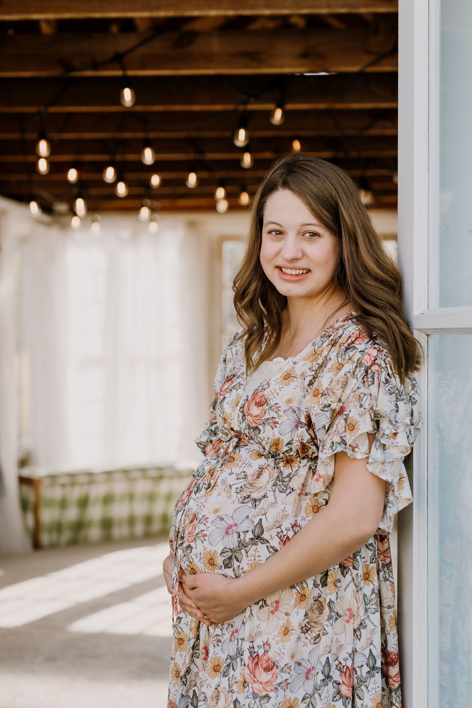 Mom smiles as she holds her bump during maternity photos at the holmstead studio in karns