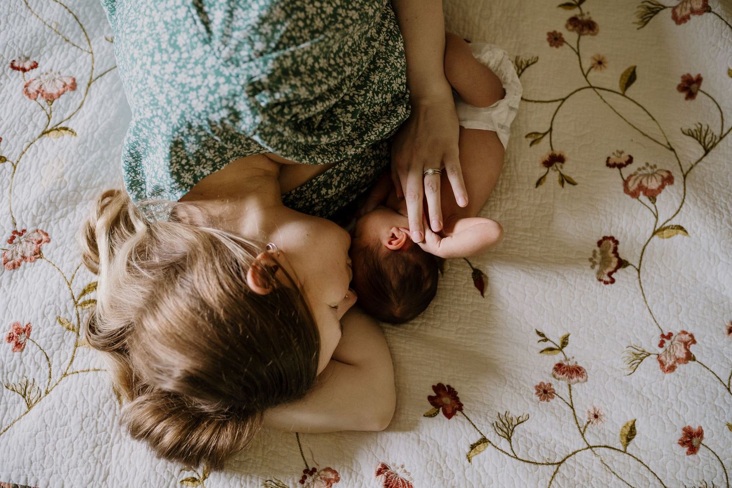 Mom lays on bed and snuggles her newborn