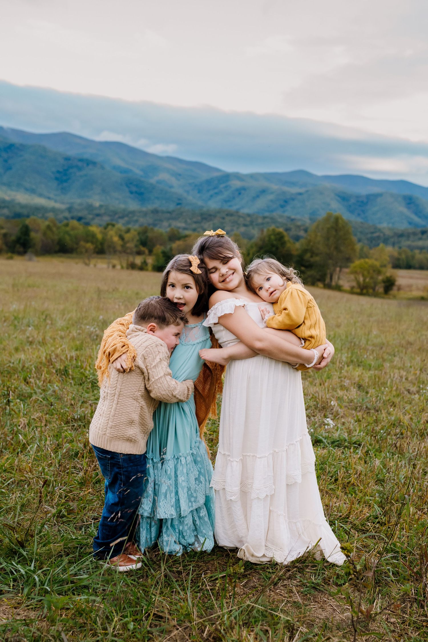 Four children cuddle together in a field at Cades Cove