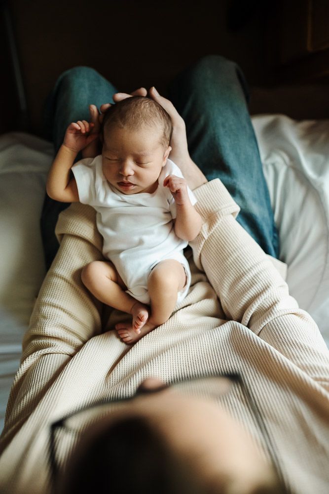 dad holding newborn baby nestled in his arms