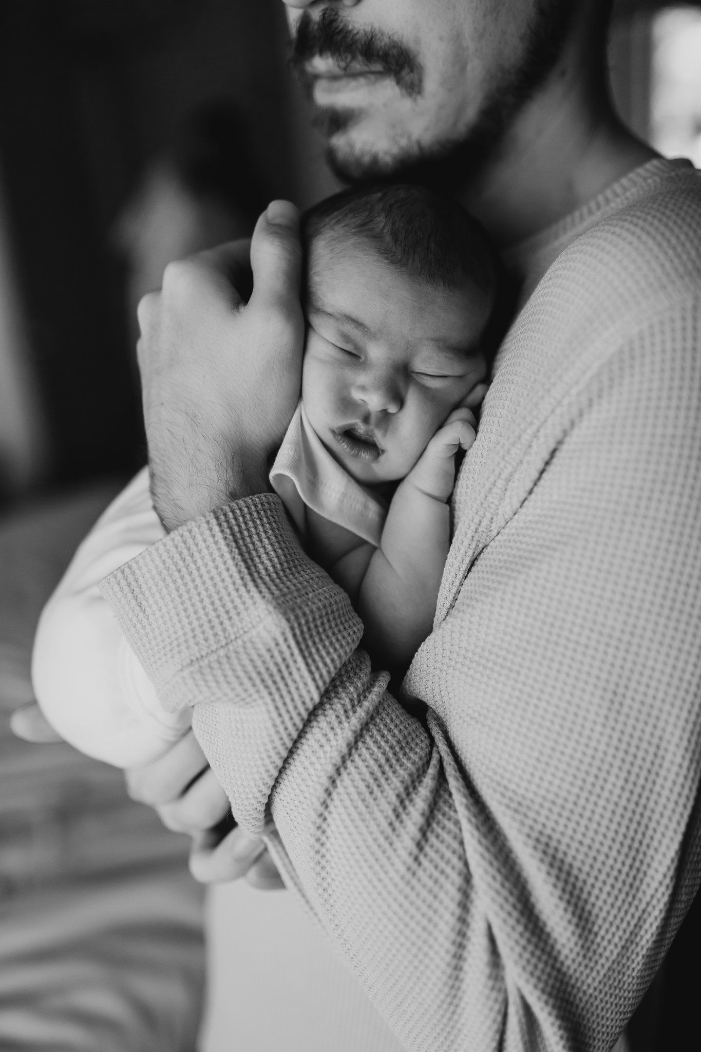 Sleeping newborn curled against dad's chest