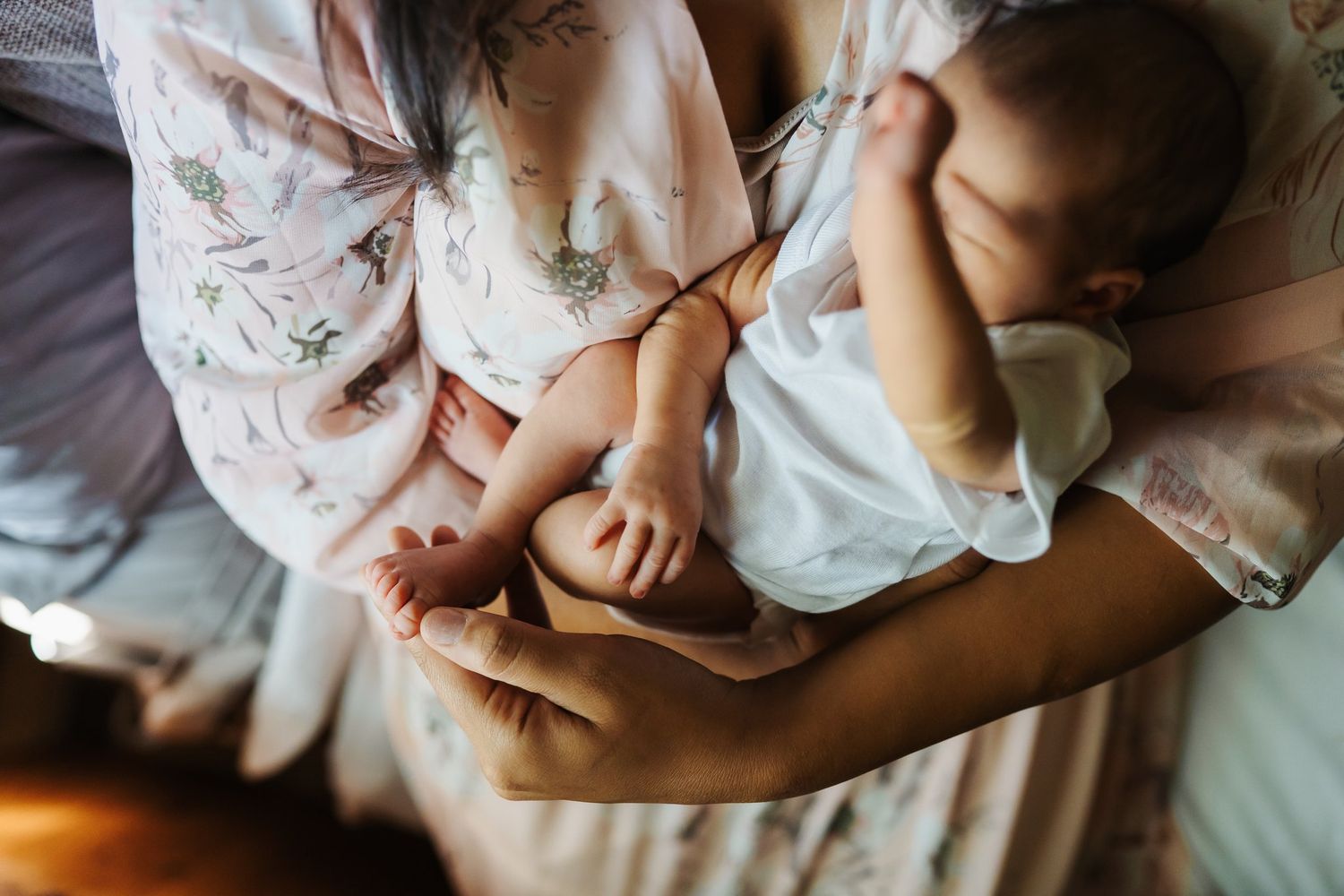 Woman holds newborn and plays with toes