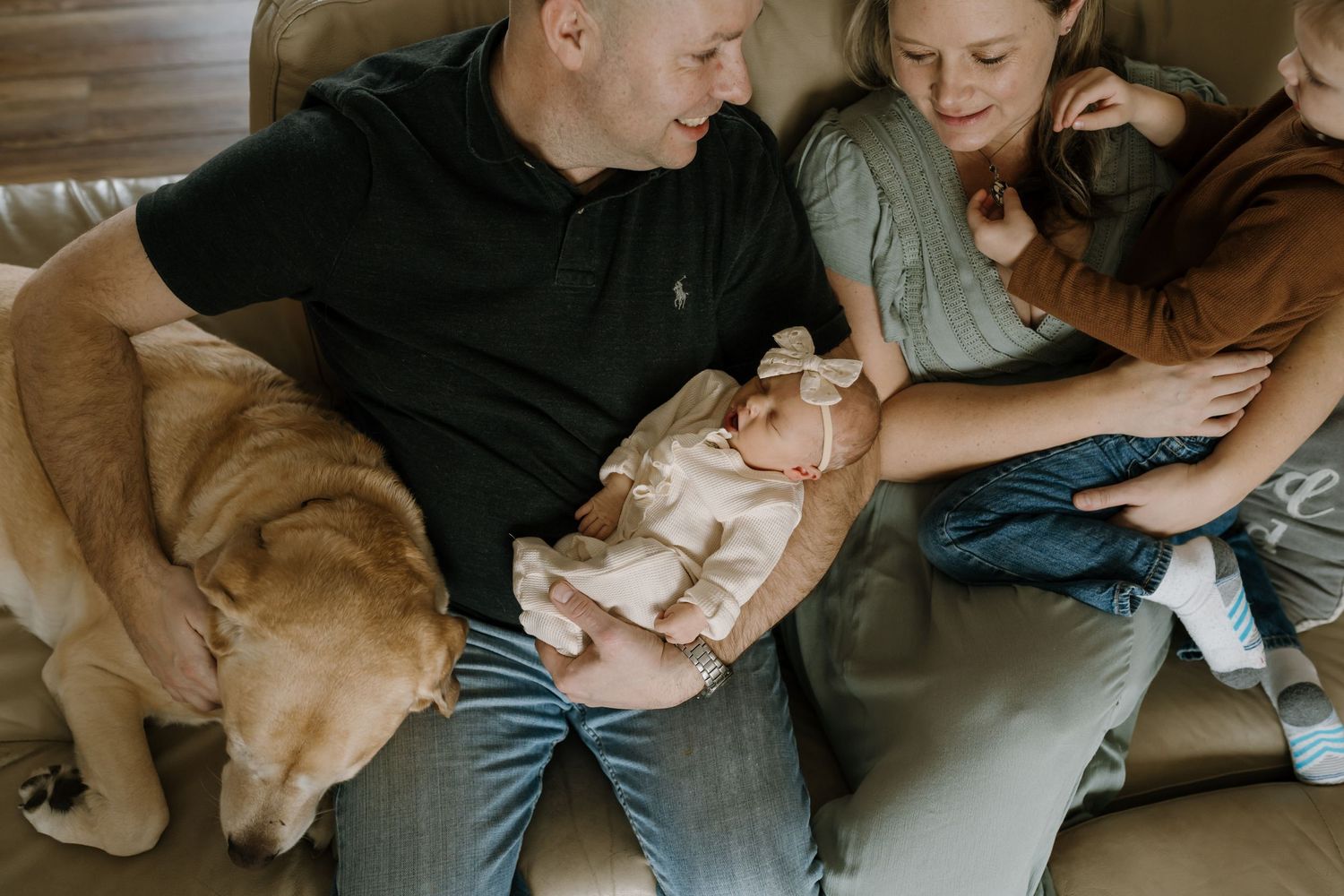 family with newborn and dog on couch