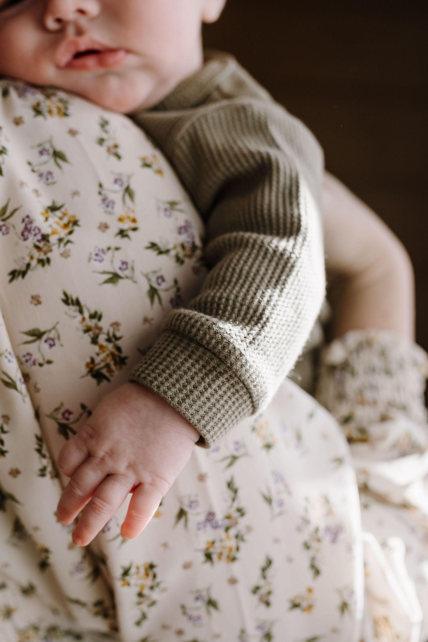 Newborn hand and lips as baby is held by mother