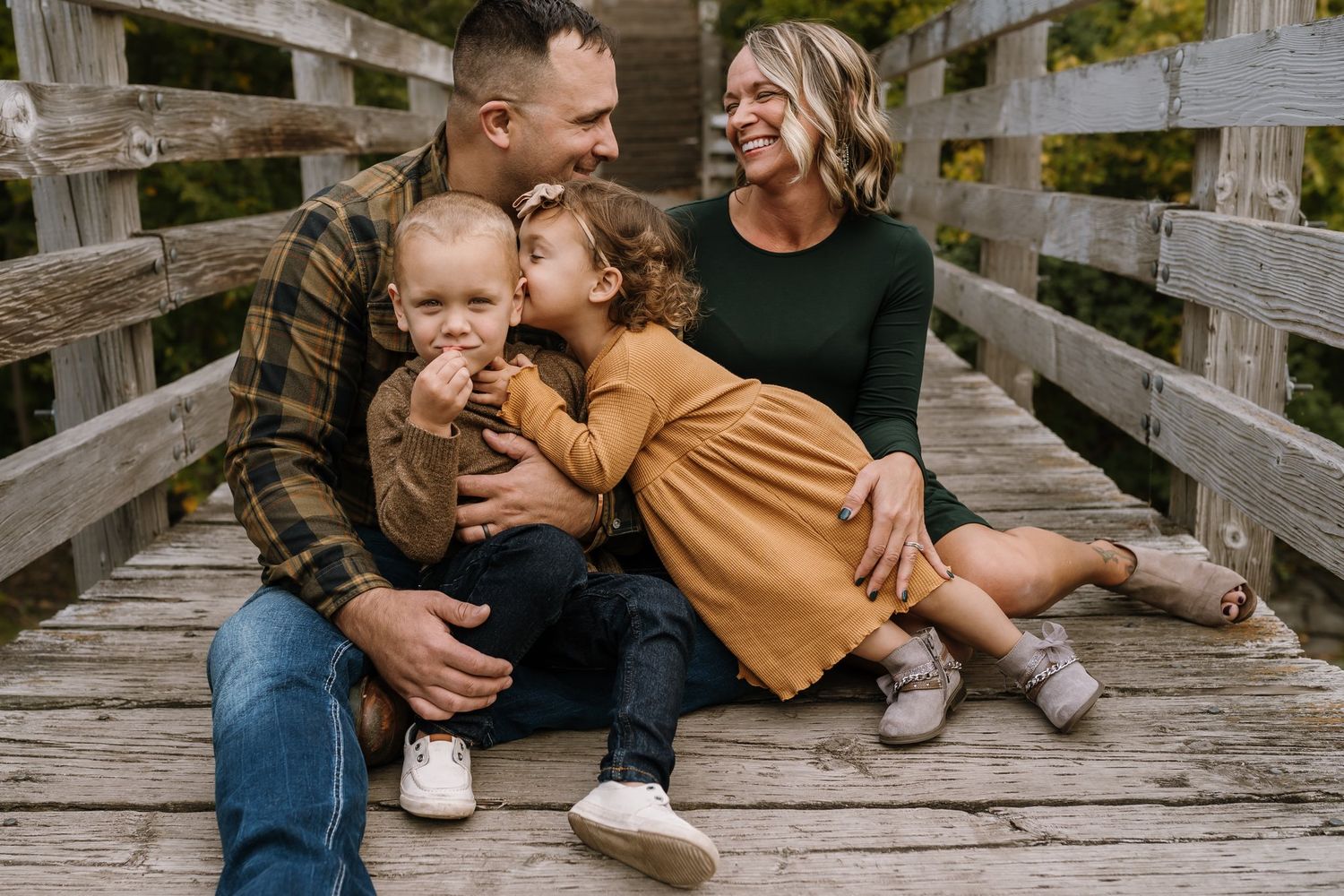 parents laughing while sister kisses brother's head during family photos in St. Cloud minnesota
