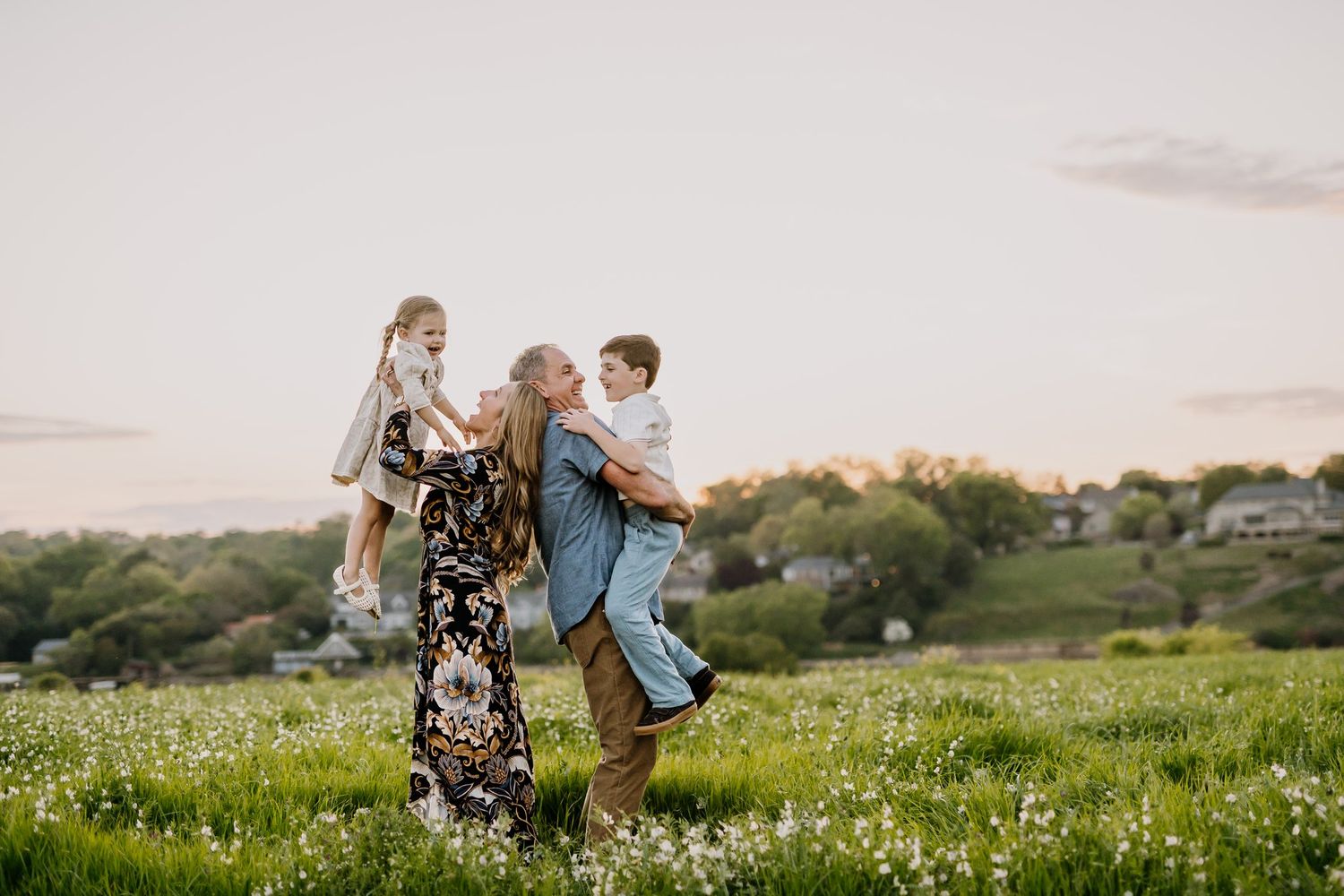 Family stands in flower field for family photos in knoxville and parents play with their kids
