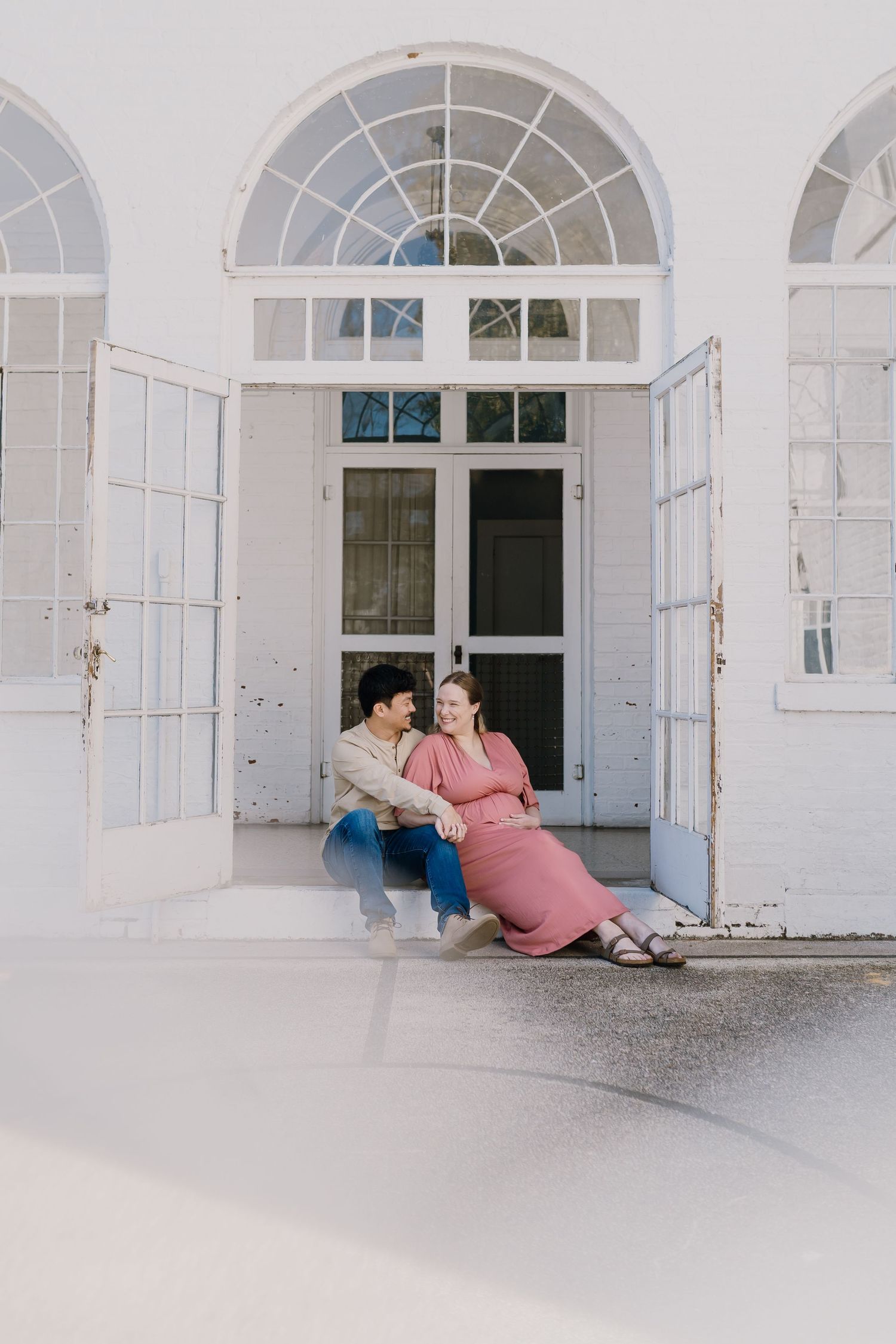 Man and woman sit framed by a historic building's door during maternity photos
