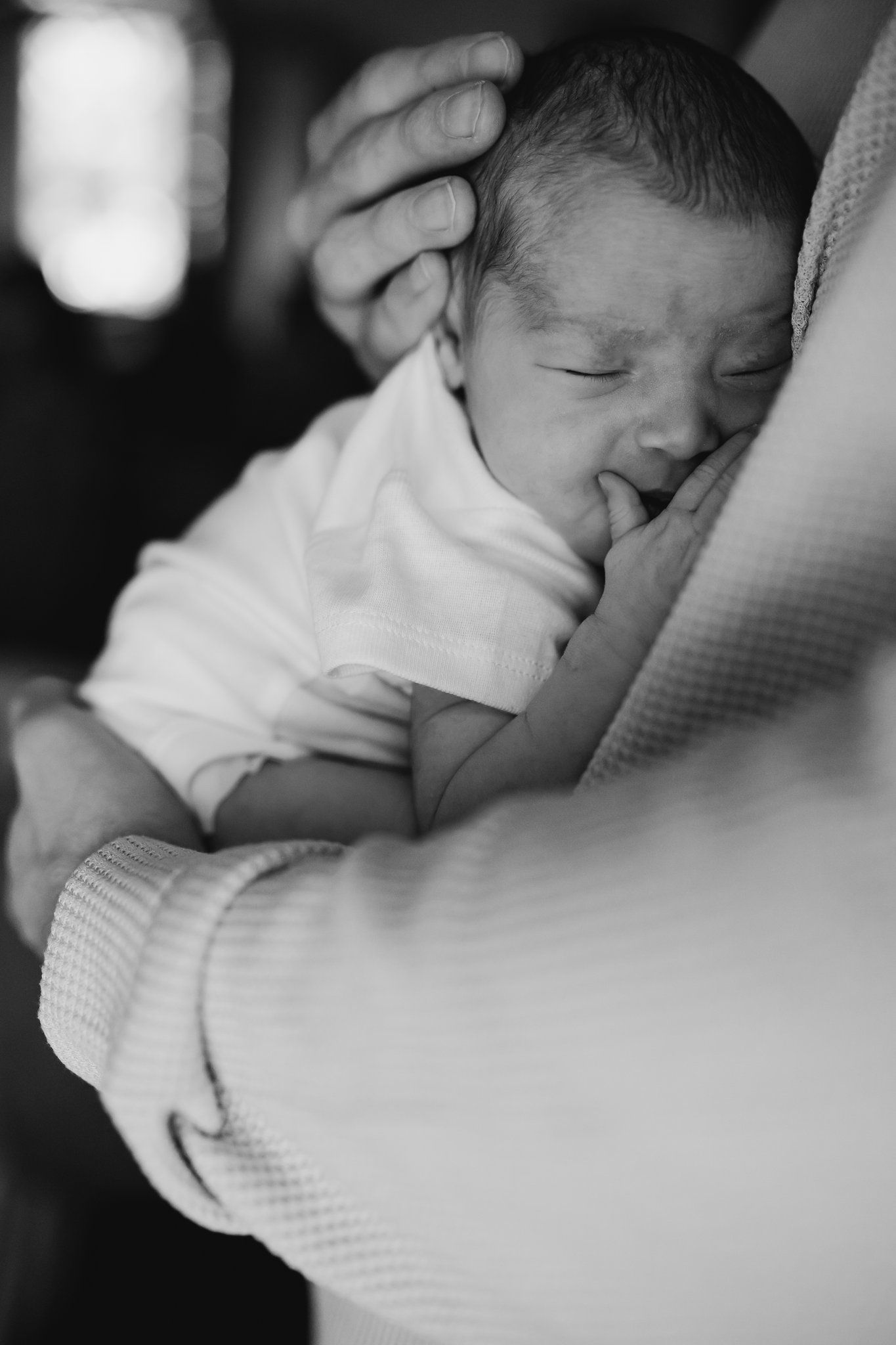 Dad snuggles his baby close during in home newborn photos