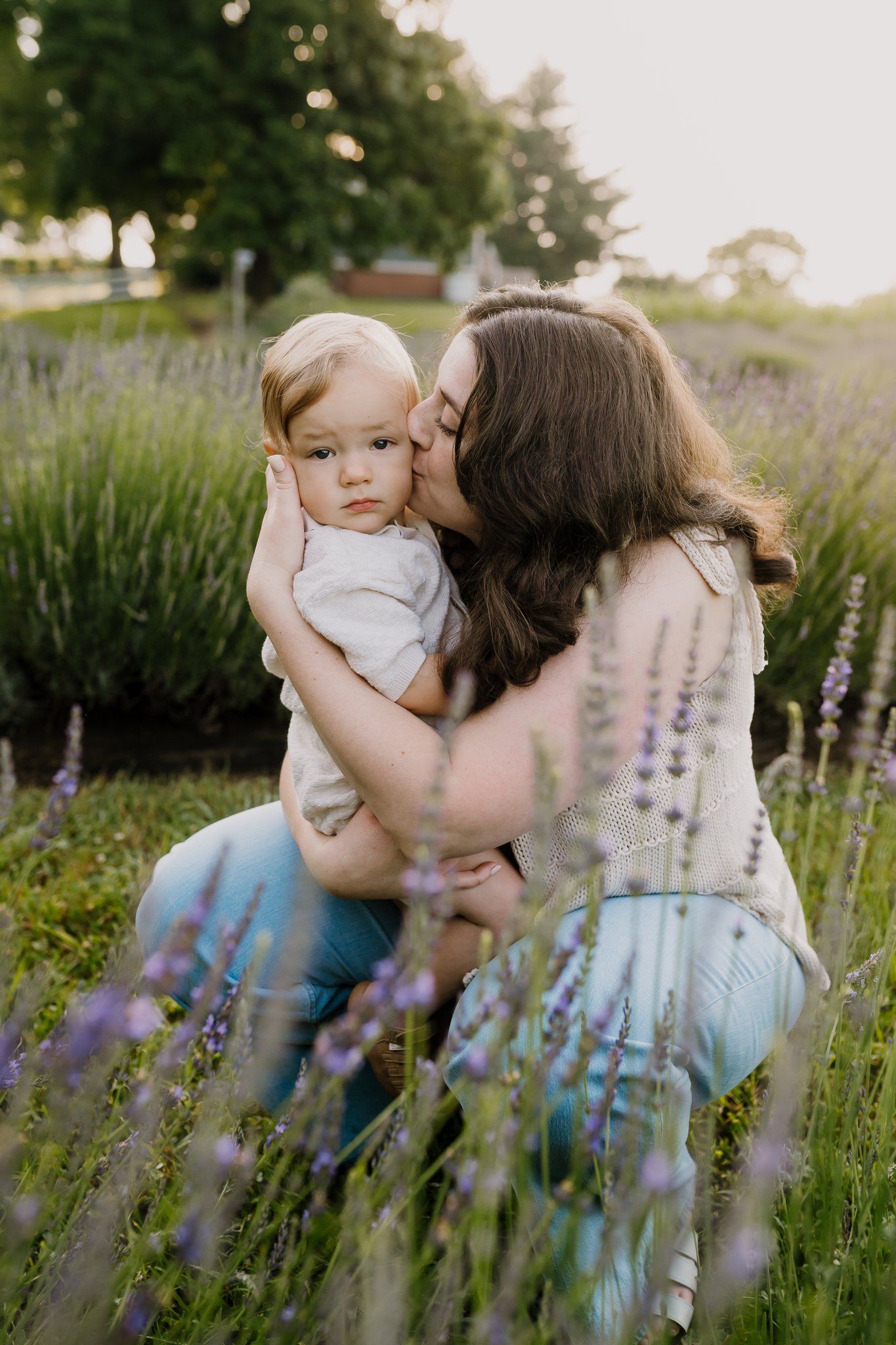 A mother kisses her toddler son in a Knoxville lavender field during golden hour.
