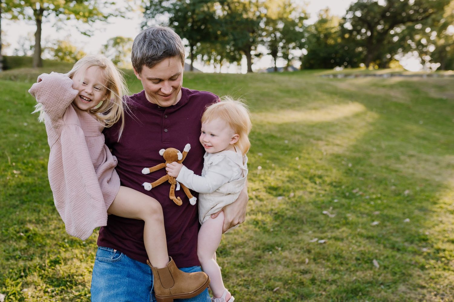 Dad bounces his two young girls as he holds them in his arms