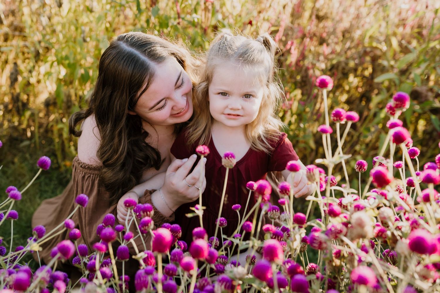 Mom snuggles her daughter as they pick flowers together in a knoxville flower field
