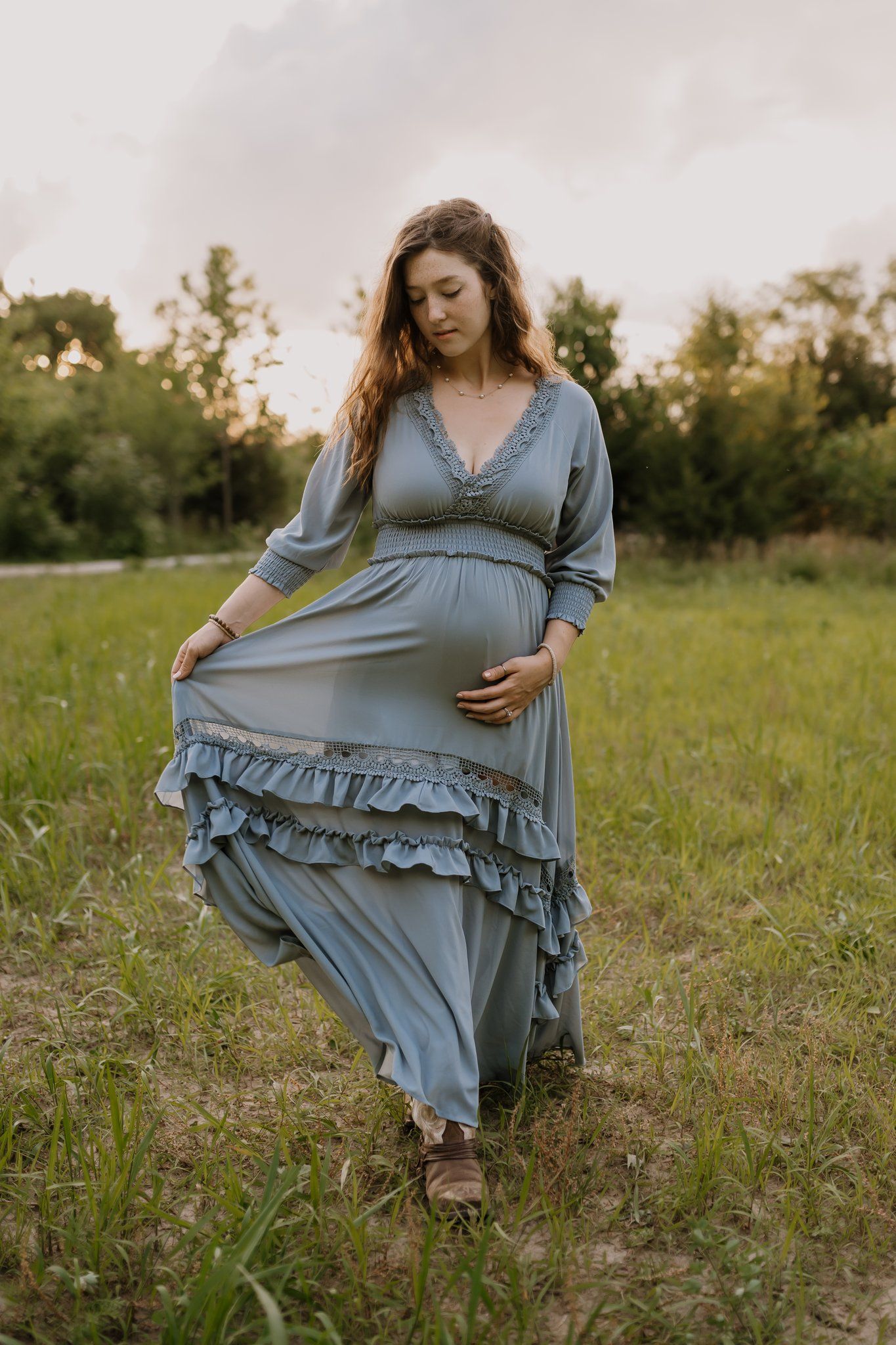 spring maternity session with a young mom walking through a green field