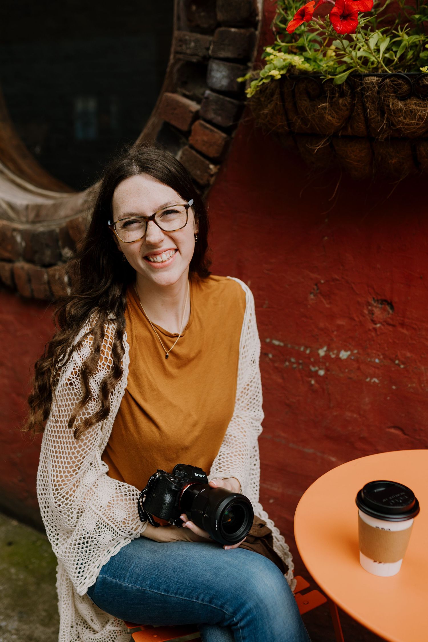 Susannah of Susannah Raye Photography, Knoxville family and newborn photographer, smiles at camera with camera in her hand and coffee cup