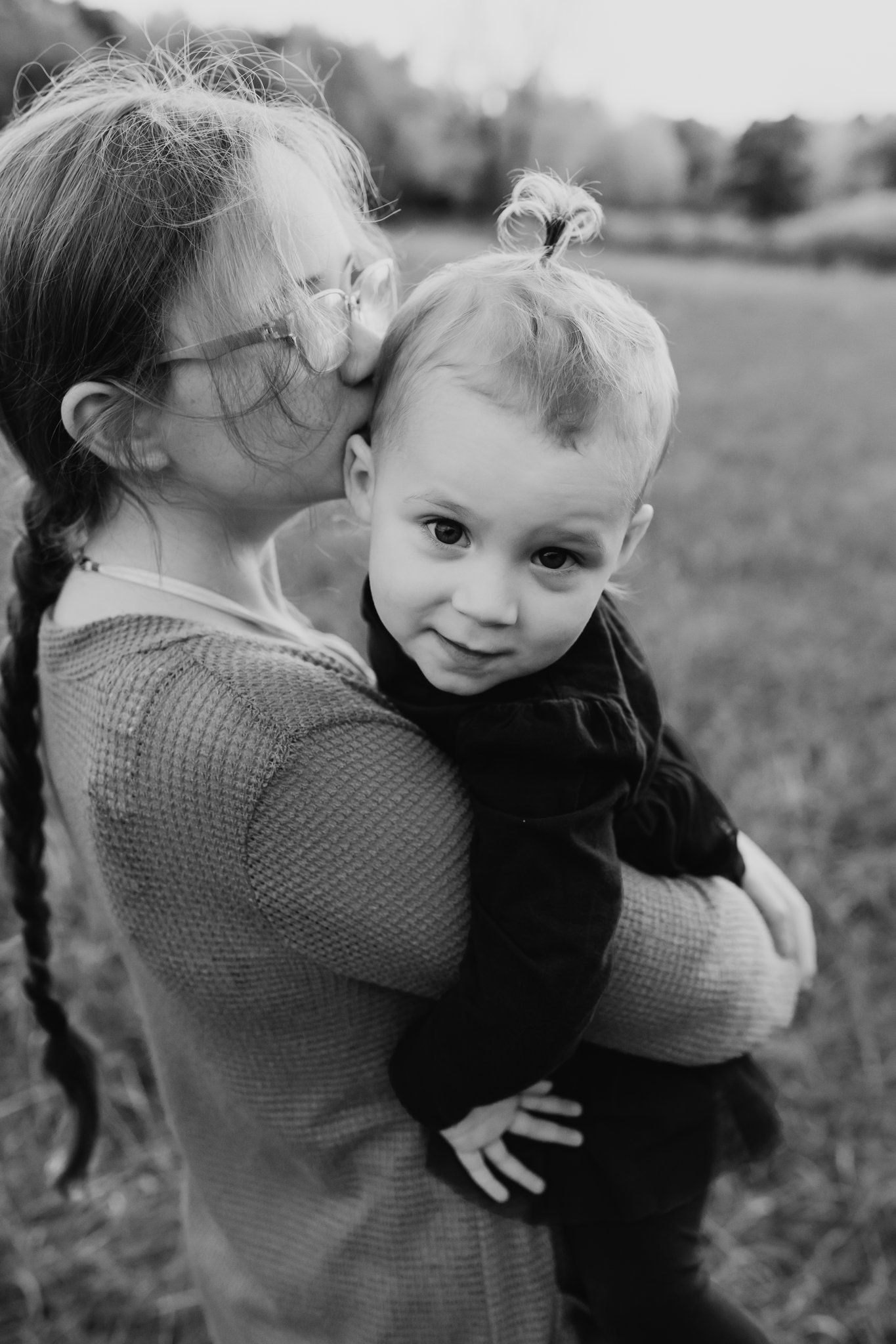 Big sister kisses her baby sister during family pictures in west knox
