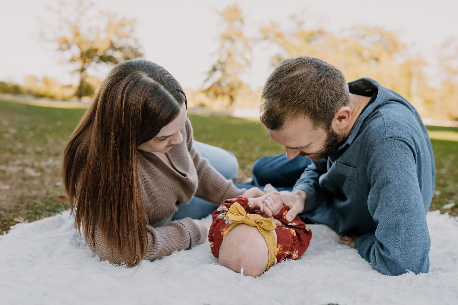 Mom and dad play with their daughter during outdoor sunset photoshoot