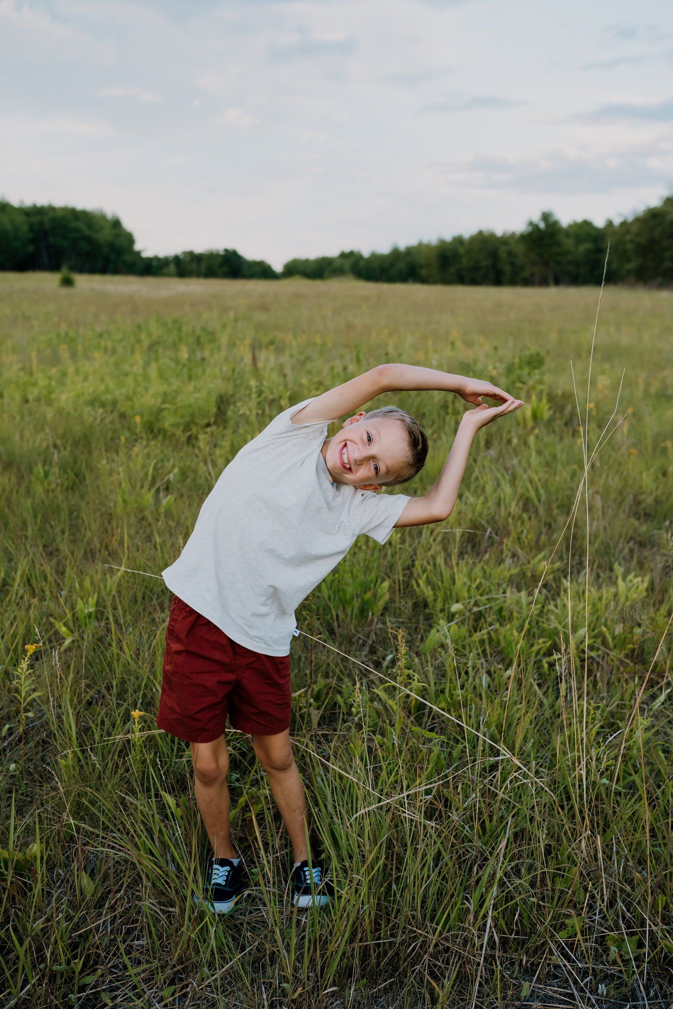 Boy does a funny pose as he stands in a field